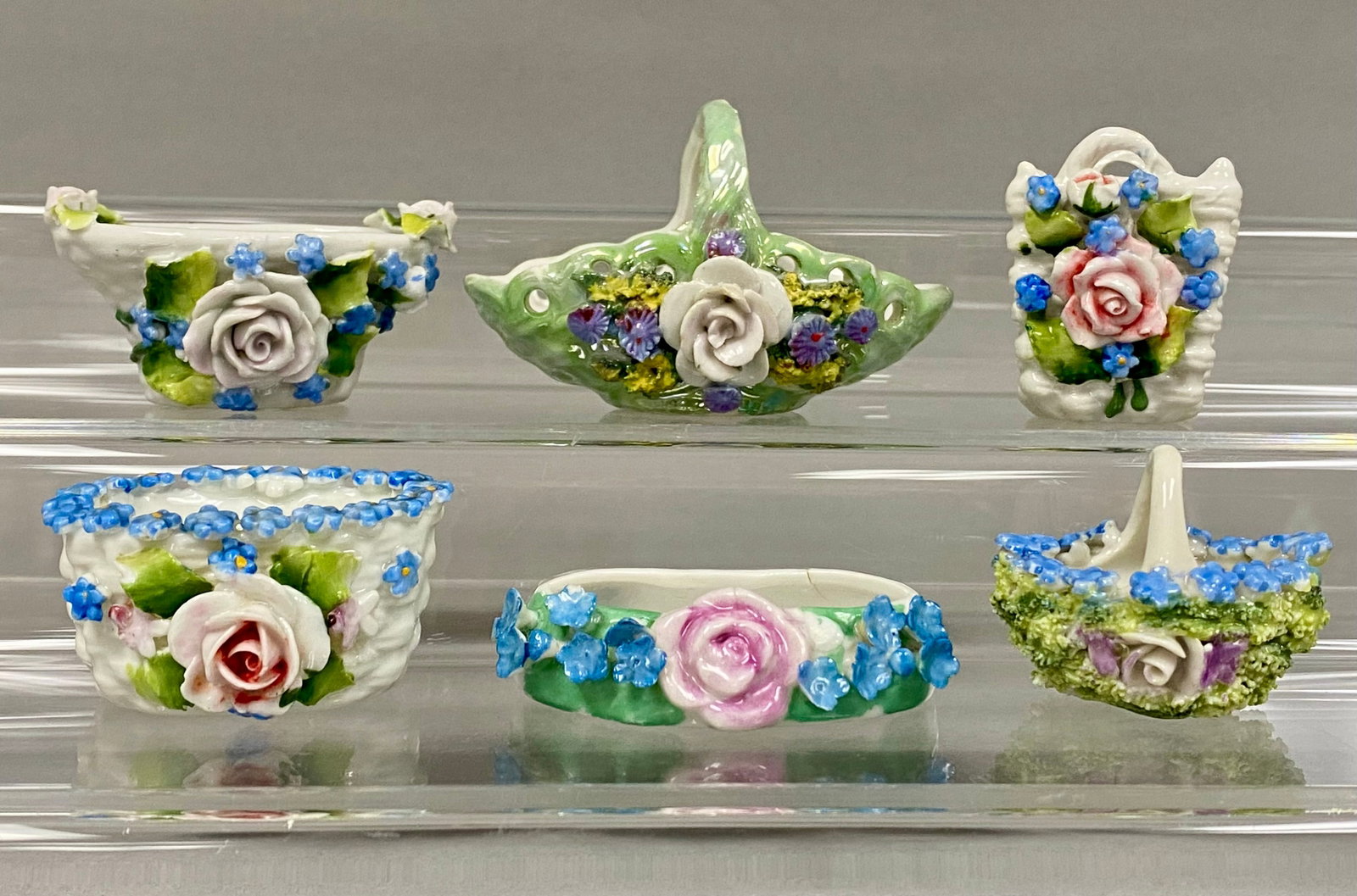 An Assortment of German Elfinware Porcelain: This collection of glazed porcelain miniatures features various forms including a reticulated basket, basket-weave bowls, and a moss-style basket. Each piece is decorated with hand-modeled applied