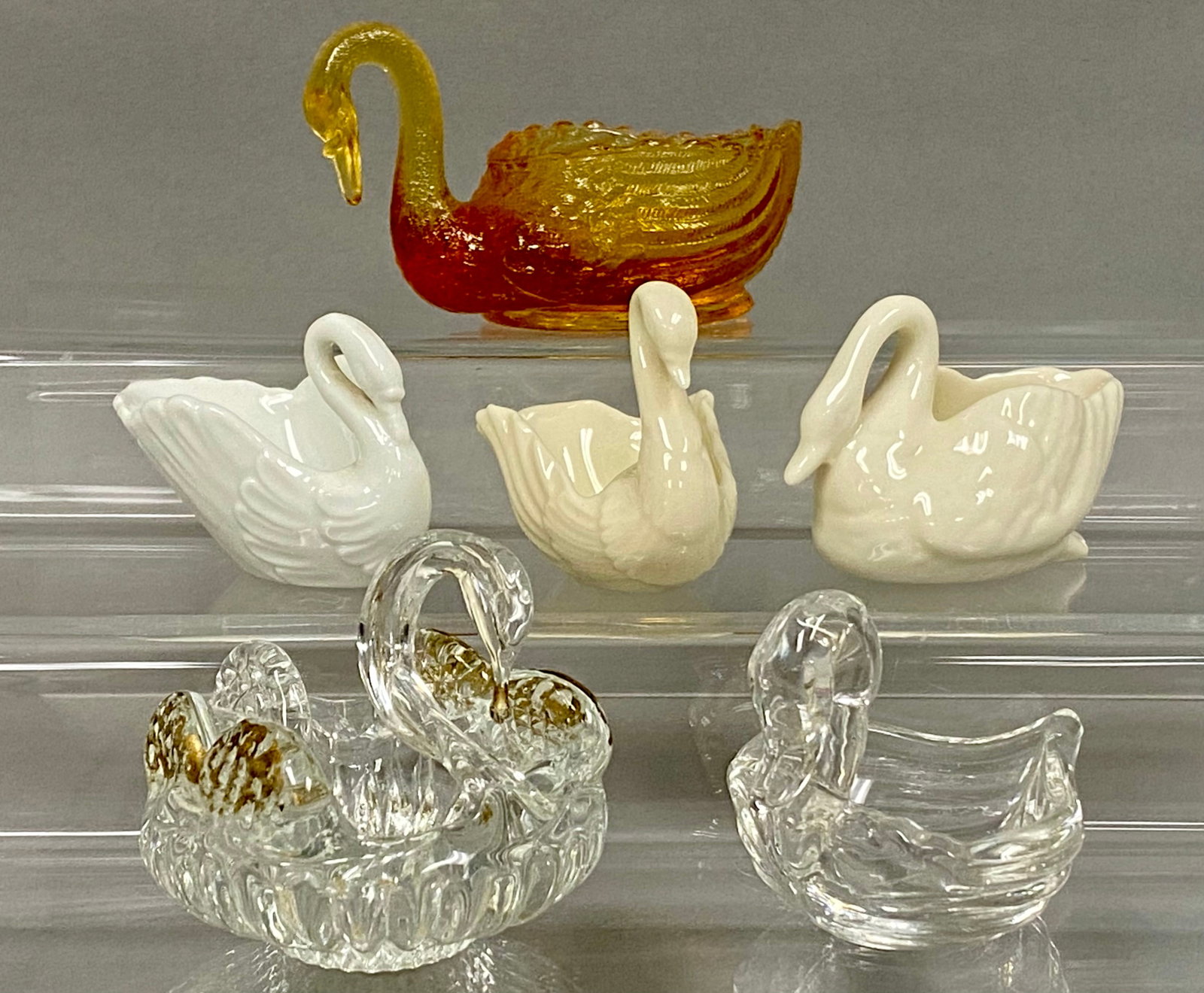 Collection of Porcelain and Glass Swans: An assortment of decorative swan-form items featuring three cream-glazed porcelain swans by Lenox and a hand-made Venetian glass swan with applied gold-tone accents. The grouping includes a pressed
