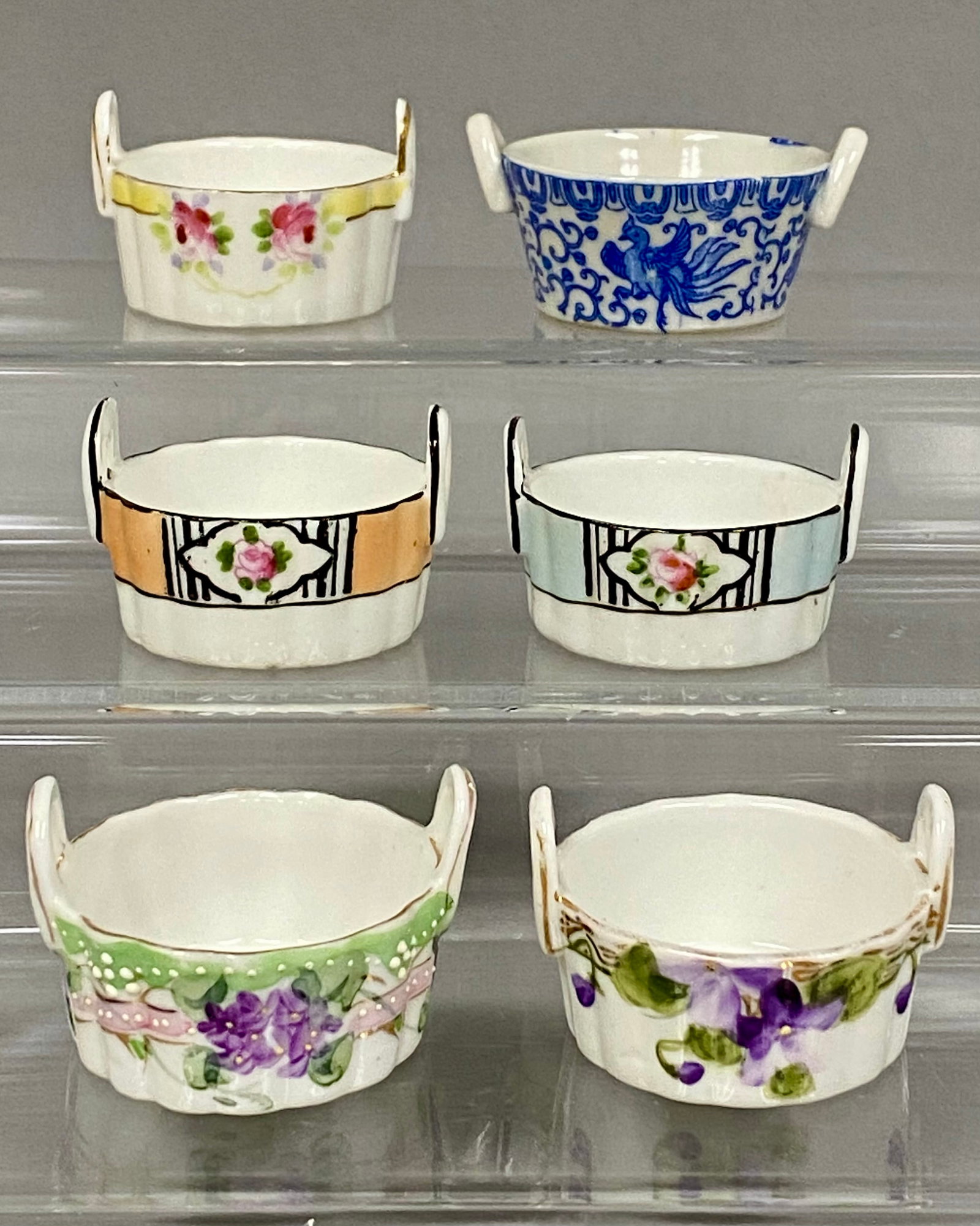 Six Nippon and Noritake Salt Cellars: A collection of six hand-painted porcelain miniature open salt cellars produced in Japan during the early twentieth century. The group features various decorative styles, including two Noritake Art De