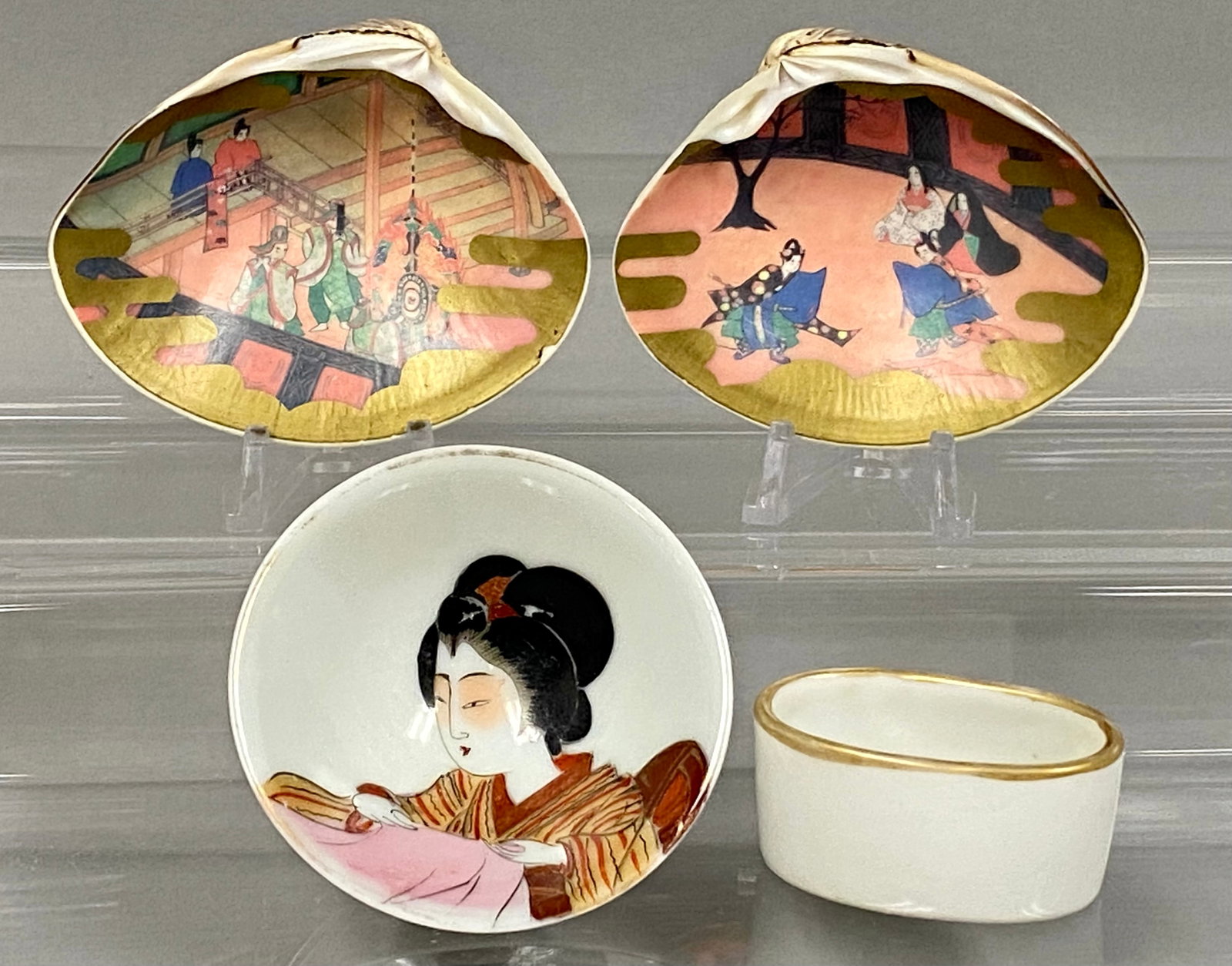 Japanese Kai-Awase Shells and Porcelain Salts: This set comprises two natural clam shells hand-painted in the Yamato-e style associated with the Kai-awase shell-matching game, a small porcelain bow, and an oval bowl. The shells depict Heian court