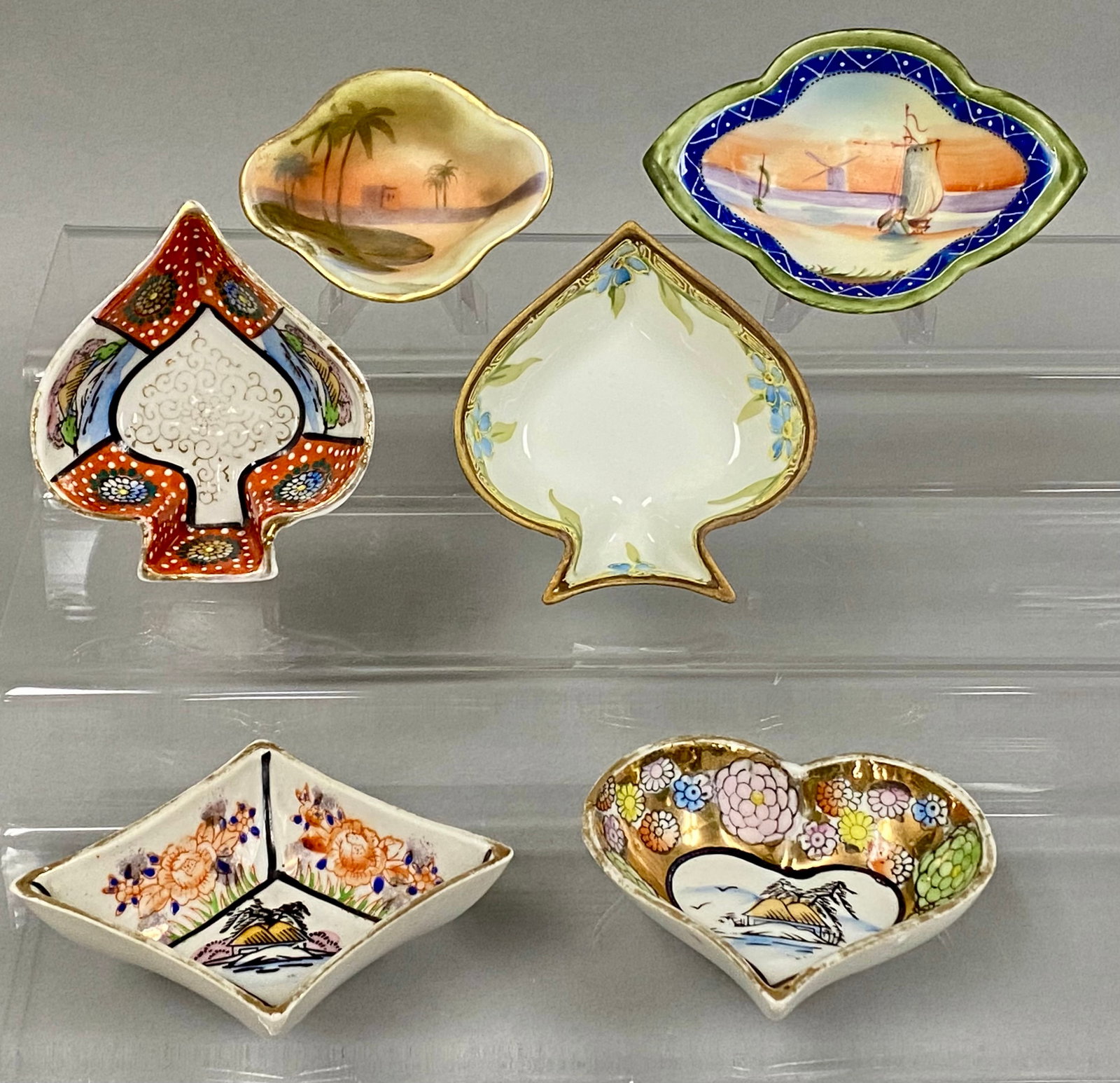 Six Japanese Hand-Painted Porcelain Dishes: This collection of six hand-painted porcelain dishes includes pieces by Nippon makers, such as Morimura Brothers, and the Takito Company. The group features various forms including heart, spade, and d