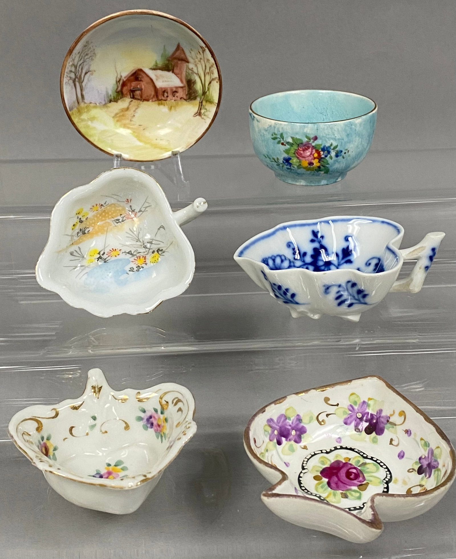 Six Ceramic Salt Cellars: This assortment features a Meissen-style porcelain leaf dish in the Blue Onion pattern with underglaze crossed swords and a James Kent Ltd. bowl with floral spray over a mottled ground. The group