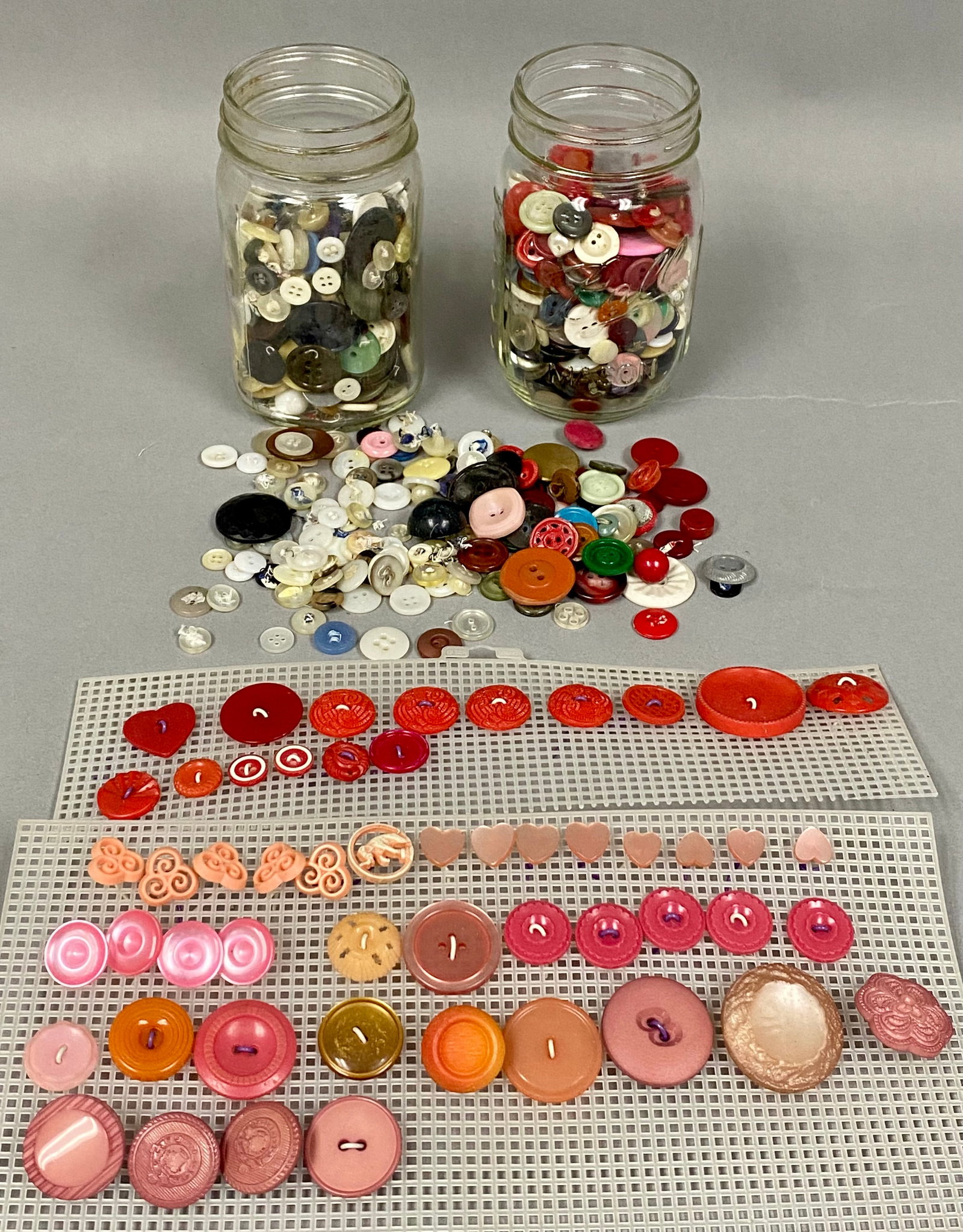 Collection of Vintage Sewing Buttons: This collection includes buttons in various materials such as plastic, glass, and celluloid. The assortment is housed in two vintage glass canning jars, including a Ball Perfect Mason jar with a zinc 