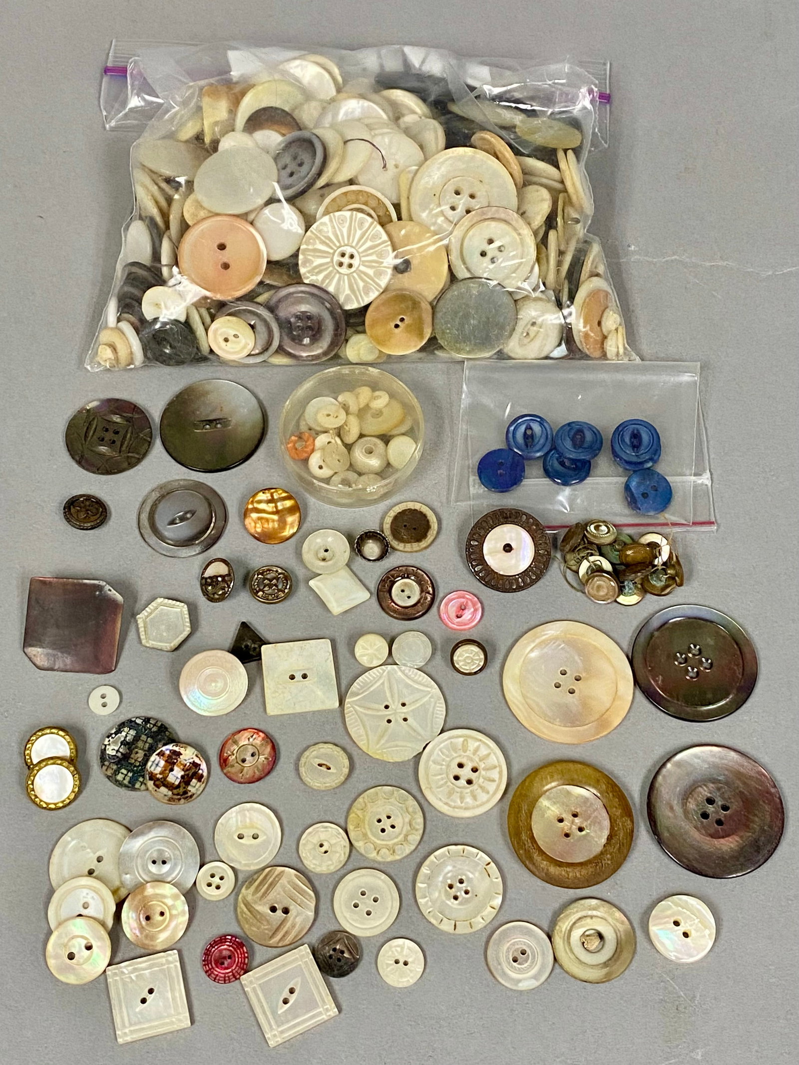 Assorted Collection of Antique Buttons: An extensive collection of vintage and antique buttons composed primarily of iridescent mother-of-pearl and carved shell. The assortment includes a wide variety of sizes and shapes, featuring decorati
