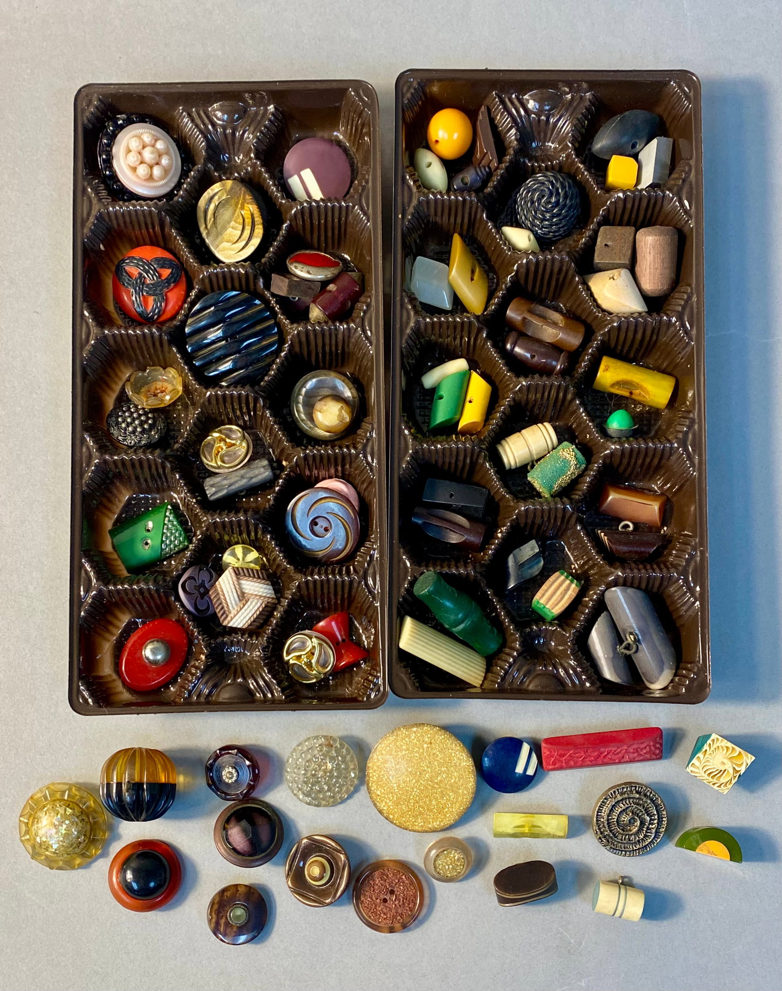 Vintage Bakelite and Plastic Button Collection: An assortment of 70 vintage buttons featuring various materials including Bakelite, Lucite, celluloid, wood, glass, and metal components. The collection displays diverse designs such as Art Deco geome
