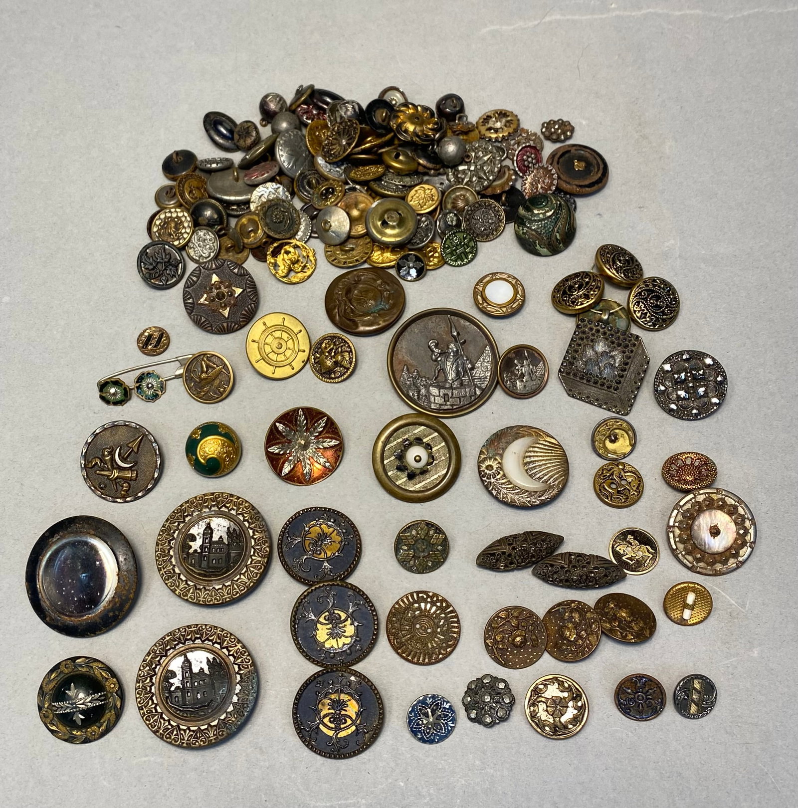 Antique and Vintage Assorted Buttons: An assortment of antique and vintage buttons featuring pictorial story themes, enameled designs, and faceted glass. The collection includes brass and mother-of-pearl examples with motifs of castles, s