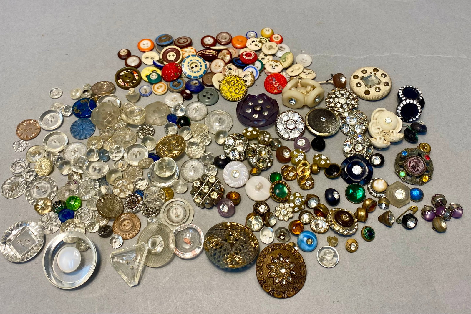 Assorted Vintage and Antique Buttons: This comprehensive collection features an array of vintage and antique buttons fashioned from glass, metal, and early plastics. The assortment includes molded clear glass, faceted rhinestone-encrusted
