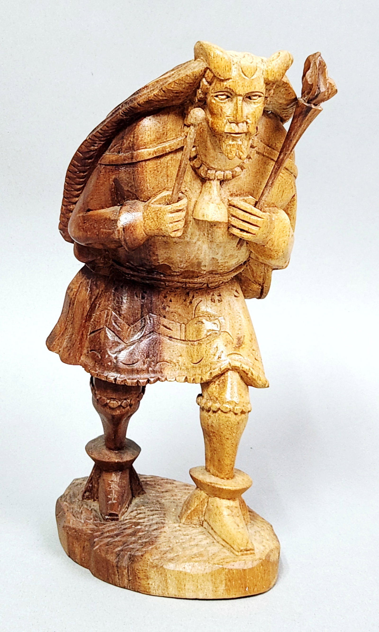Ecuadorian Folk Art Warrior: This hand-carved wood sculpture depicts a shamanic or warrior figure wearing a horned mask and a textured fur-like cloak. The carving features a distinctive two-tone stained finish and is signed with 