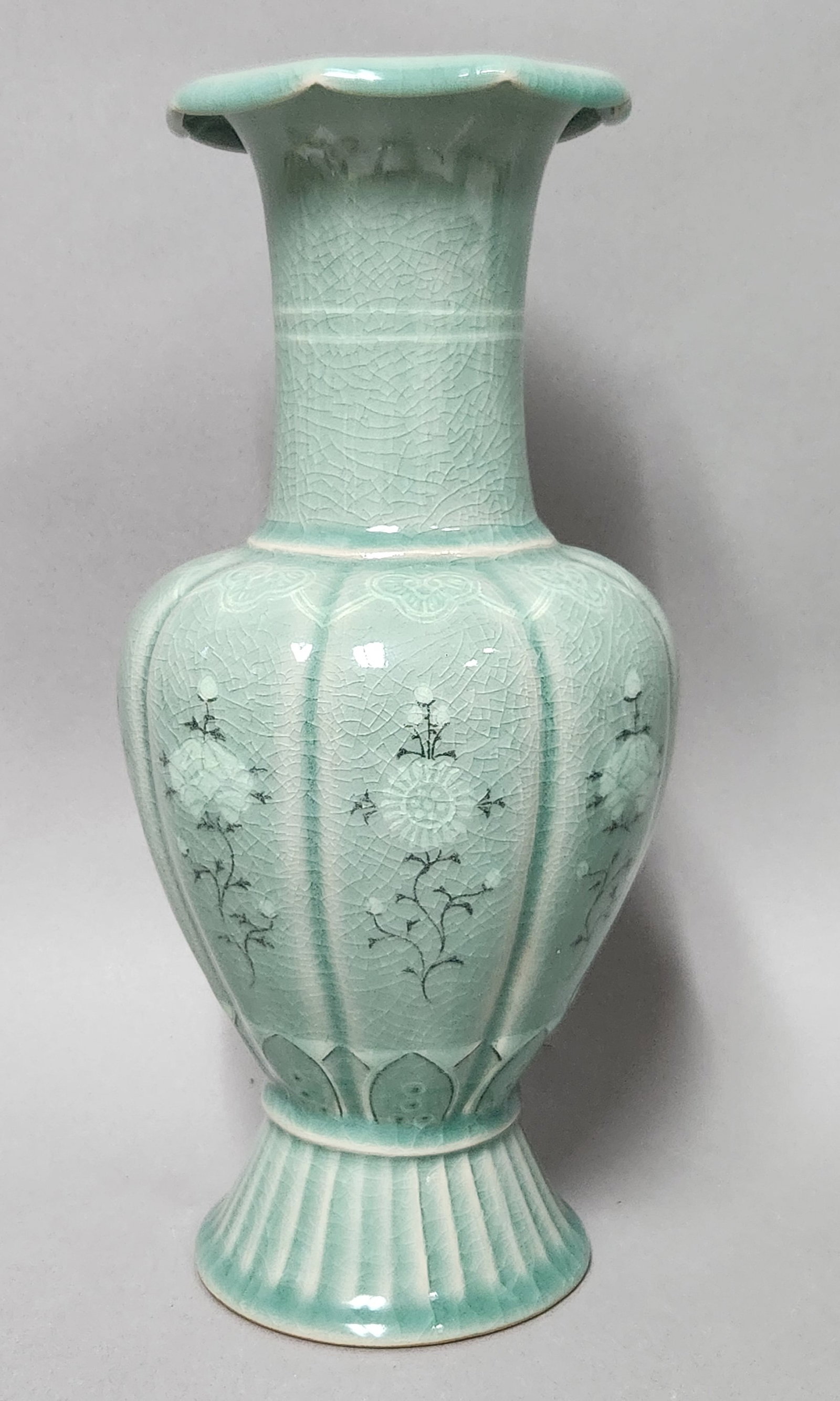 Korean Inlaid Celadon Floral Vase: A light green celadon-glazed ceramic vase featuring inlaid floral motifs and a lobed body. The surface is finished in a pale green glaze with a dense network of crackle. The vessel stands on a fluted