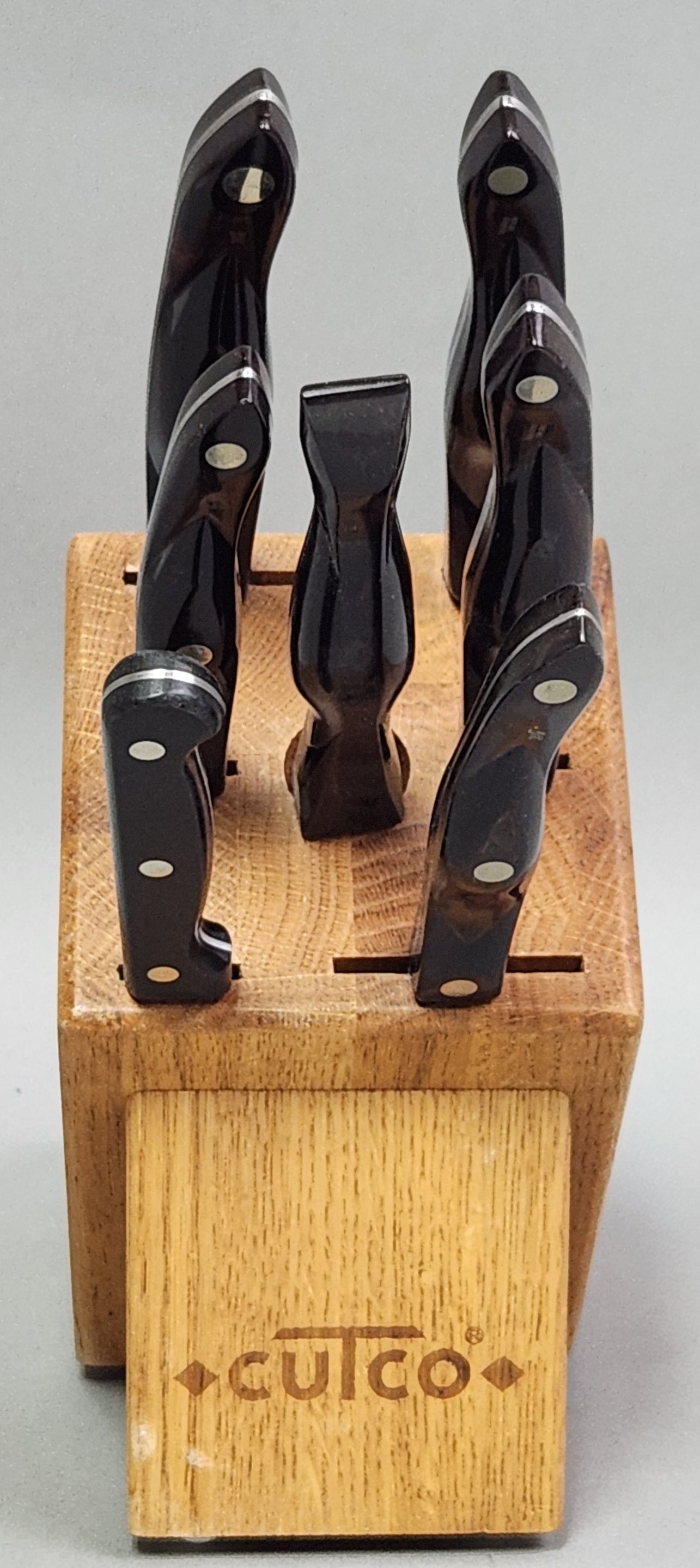 Cutco Cutlery Set: This set of kitchen implements features Cutco stainless steel blades with ergonomic dark brown marbled handles, marked with model numbers and dated 1990. One non-matching paring knife by GoodCook is