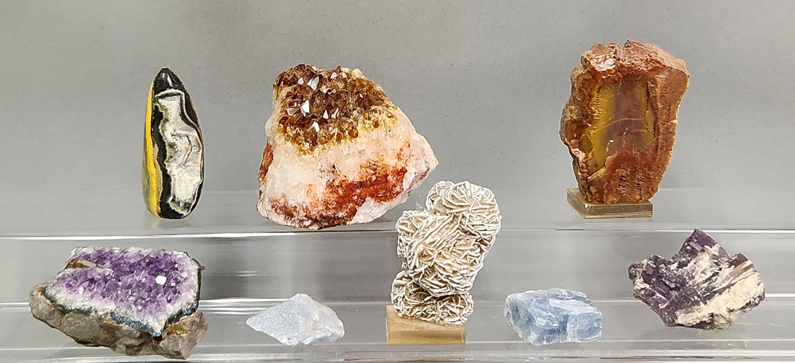 Collection of Mineral Specimens: A group of geological specimens including polished bumblebee jasper, a heat-treated amethyst cluster, a desert rose selenite cluster on an acrylic mount, and a lepidolite specimen. The assortment also
