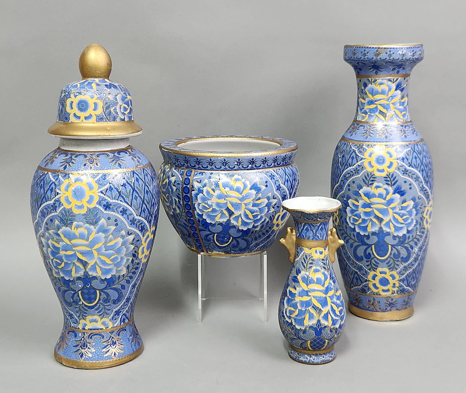 Chinese Porcelain Vessels: A collection of four pieces of twentieth-century Chinese export porcelain featuring a matching pattern of yellow and light-blue peonies on a medium-blue ground. The collection shows significant rubbin