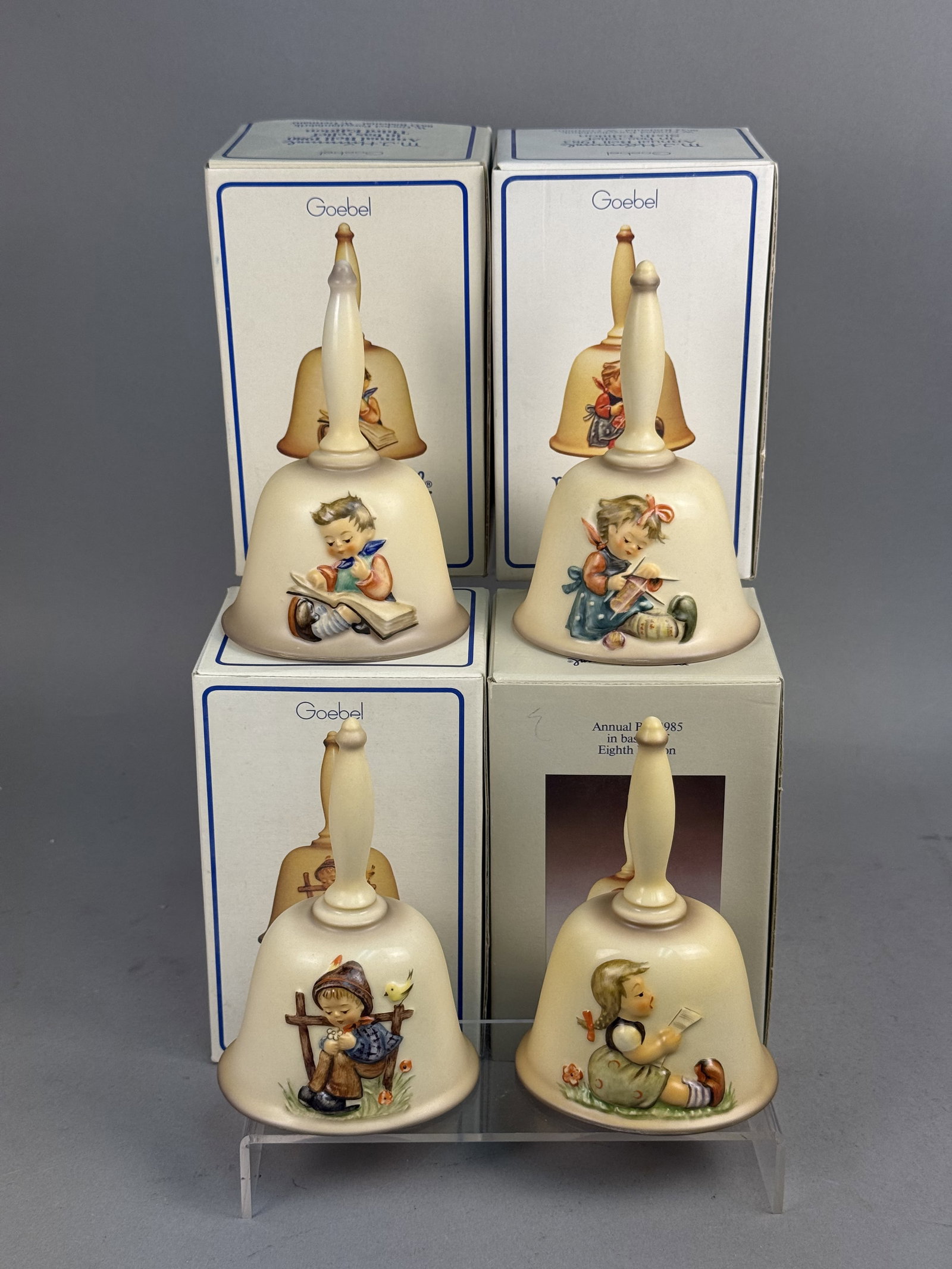 Four Goebel Hummel Annual Bells: A collection of four M.I. Hummel annual collector's bells manufactured by Goebel in West Germany. Crafted from hand-painted ceramic with a matte finish, each piece features a bas-relief figure represe