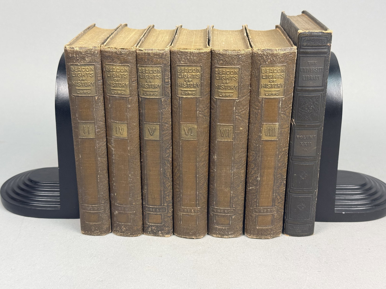 Seven Vintage Decorative Hardcover Books: This collection includes six volumes of Beacon Lights of History by John Lord and one volume of The University Library. The history volumes feature textured brown cloth bindings with a decorative