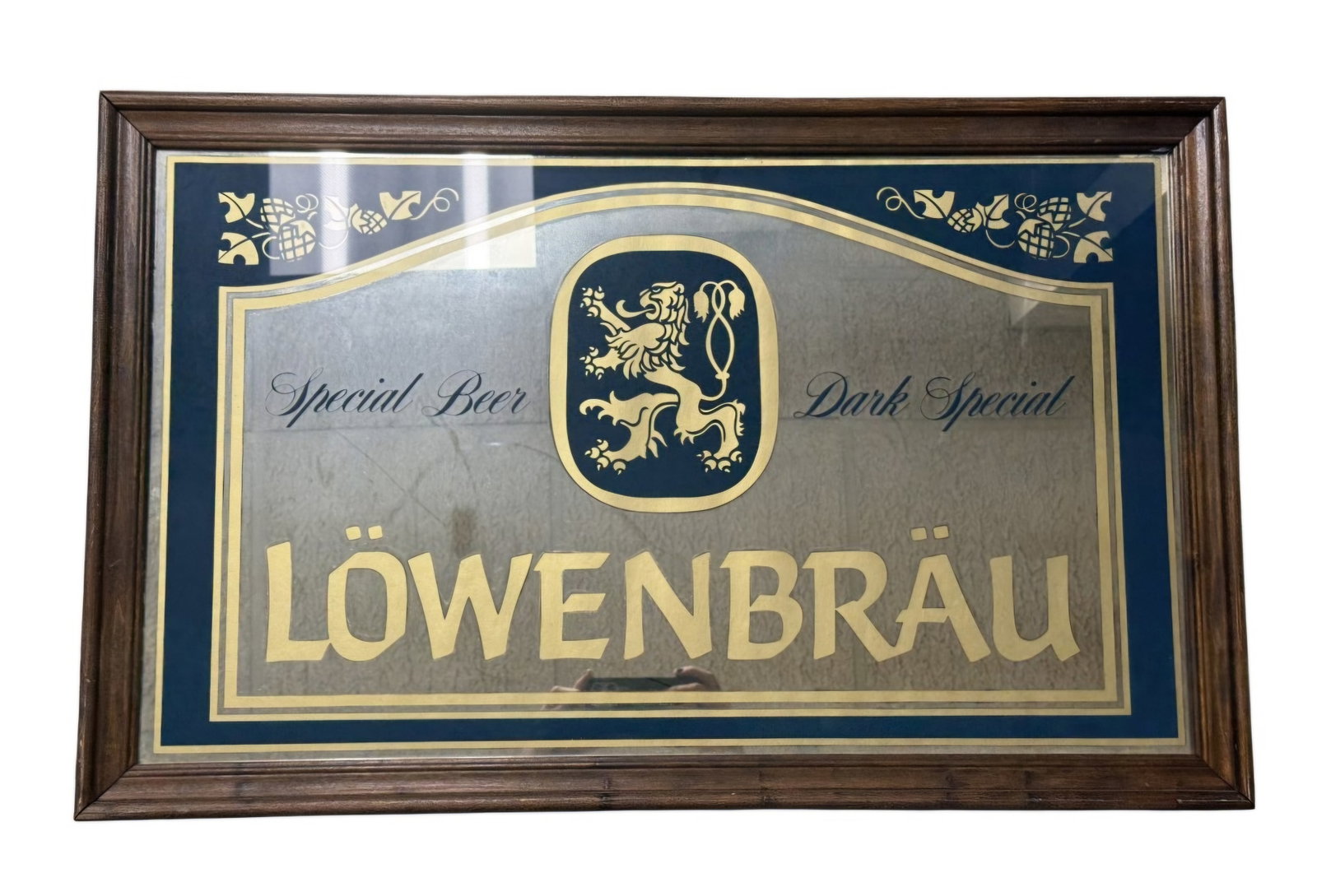 Vintage Lowenbrau Advertising Beer Mirror: A vintage Lowenbrau advertising mirror featuring gold-tone and navy blue graphics within a dark wood frame. The central design includes the brewery's signature rampant lion crest flanked by script