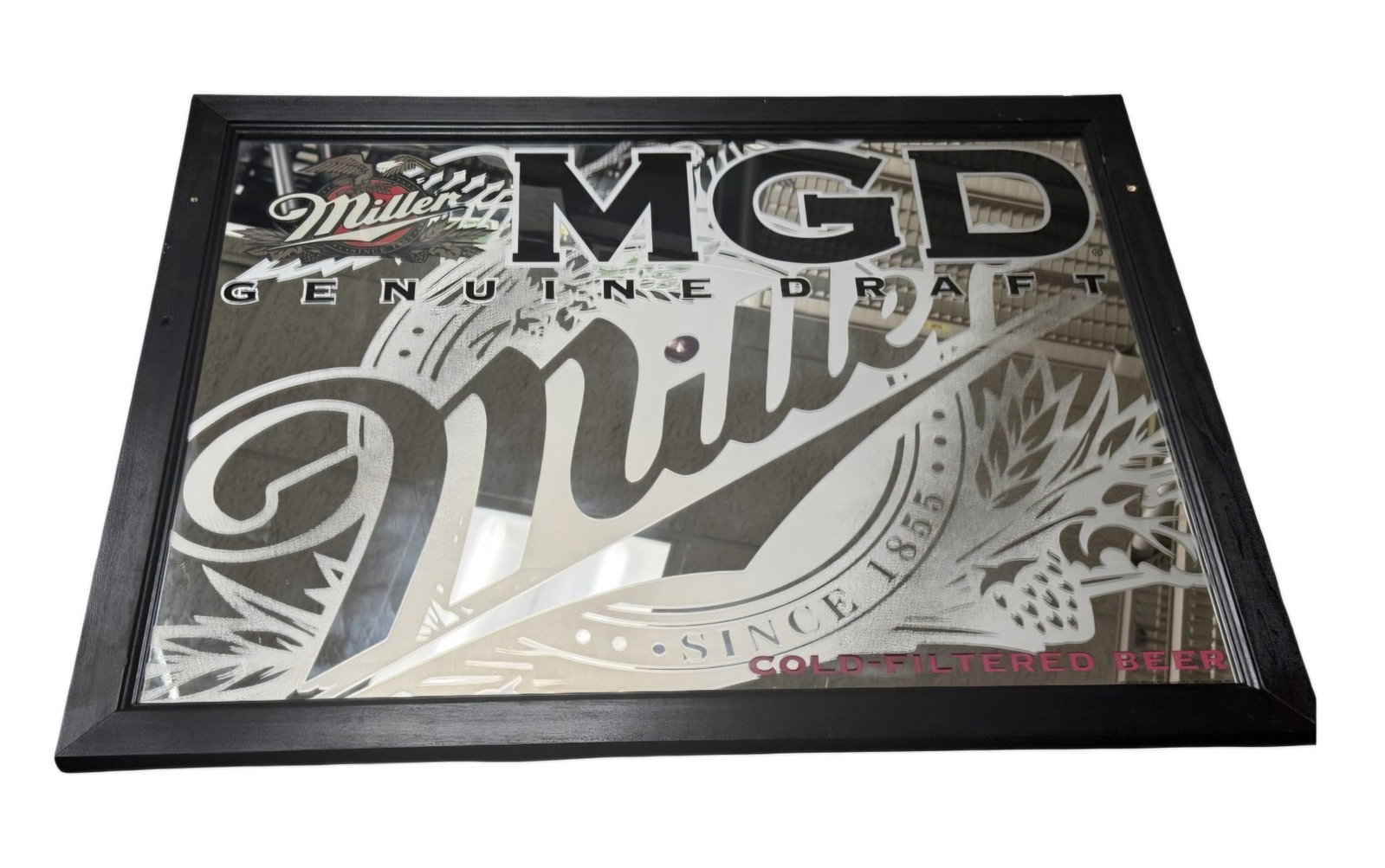 Miller Genuine Draft Advertising Mirror: This large format advertising mirror features the Miller Genuine Draft logo with stylized script and detailed hop and wheat graphics. The design incorporates clear mirror sections, frosted
