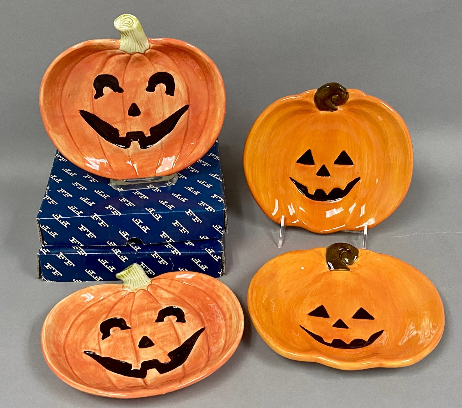 Set of Ceramic Pumpkin Plates: This set consists of two 1987 Fitz and Floyd earthenware canap?© plates and two larger pumpkin dishes by Palm Tree Co., Ltd. The Fitz and Floyd pieces feature incised marks and branded boxes,