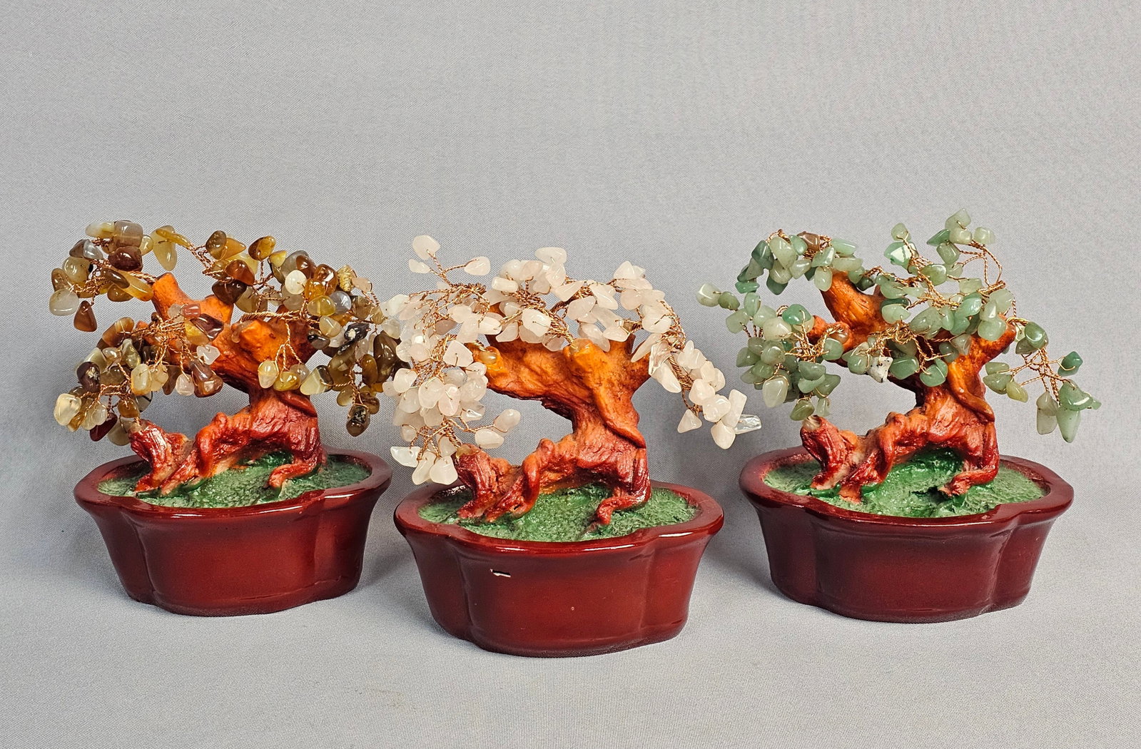 Trio of Gemstone Bonsai Trees: A trio of miniature bonsai-style trees featuring various semi-precious stone chips likely including rose quartz, aventurine, and agate varieties. Each tree is constructed with twisted gold-tone wire
