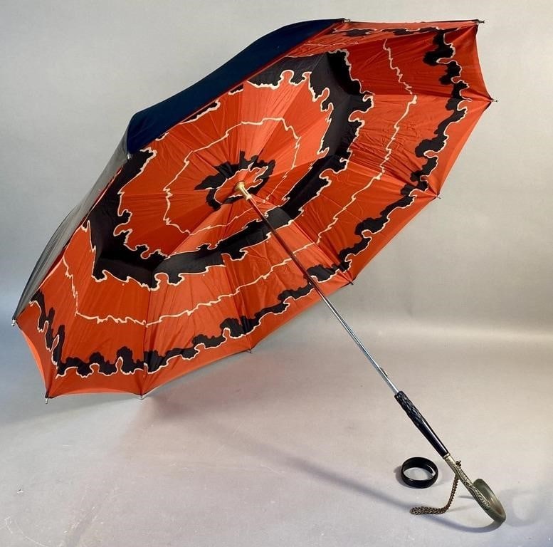 Vintage Double Layered Stick Umbrella: A vintage double layered stick umbrella, characterized by concentric wavy black and white lines on a reddish-orange background. The ornate crook-style handle, with a fine metal wrist chain, is