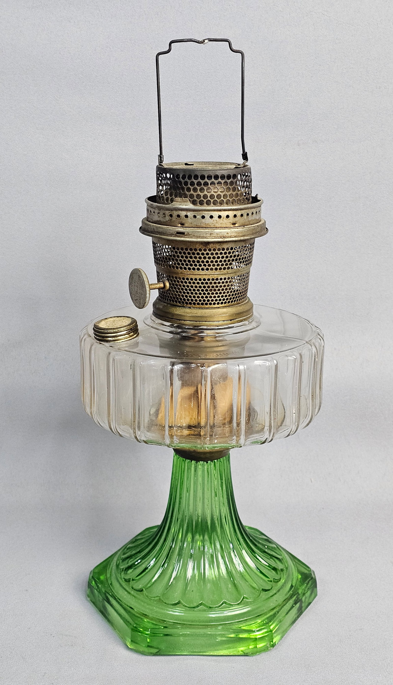 Aladdin Model B Mantle Oil Lamp: This antique Aladdin Nu-Type Model B mantle lamp features a clear ribbed glass font supported by a vibrant green pressed glass fluted pedestal base. The brass burner assembly is stamped with maker
