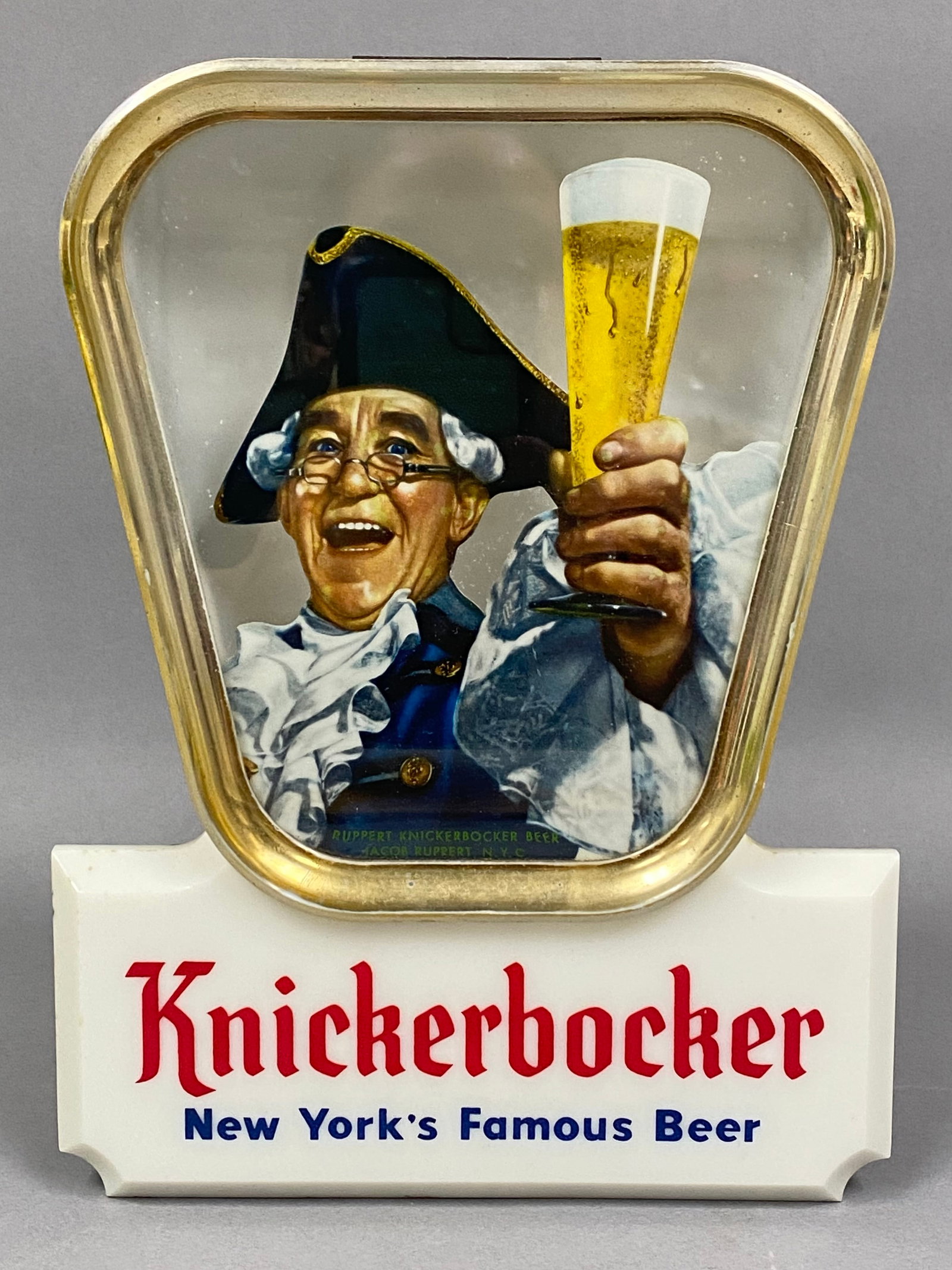 Knickerbocker Beer Price Brothers Lighted Sign: A Price Brothers countertop lighted advertising sign produced for the Jacob Ruppert Brewery, featuring the Father Knickerbocker mascot raising a glass. The construction consists of a molded plastic fr