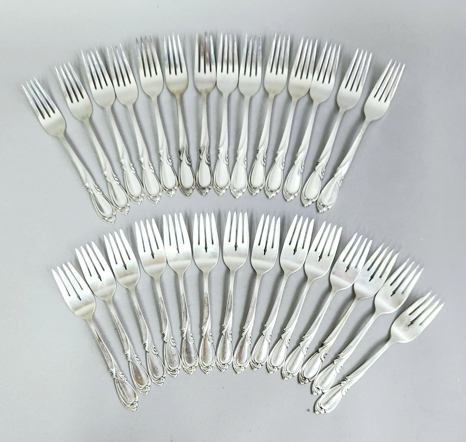 International Silver Sterling Flatware 2,065.06 Grams: A set of International Silver Company sterling silver flatware in the Rhapsody pattern, characterized by scrolling floral and foliate motifs. The service includes fourteen dinner forks, fourteen salad