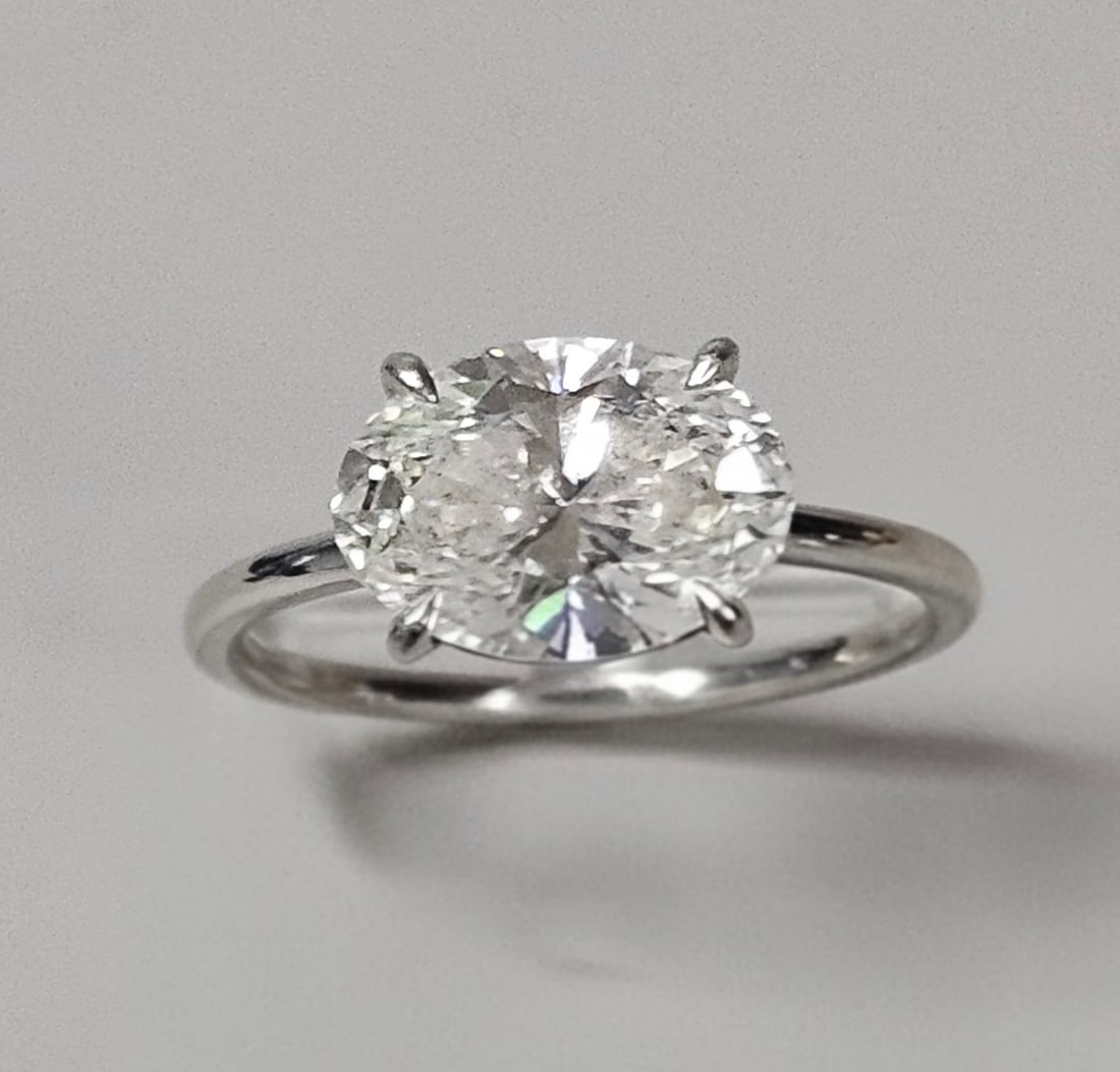 Platinum Oval Lab Grown Diamond Ring 5.4 Grams: This ring is constructed from solid platinum and features a large, four-prong set oval-cut lab grown diamond measuring approximately 10 by 8 millimeters. The 5.4-gram setting features a classic
