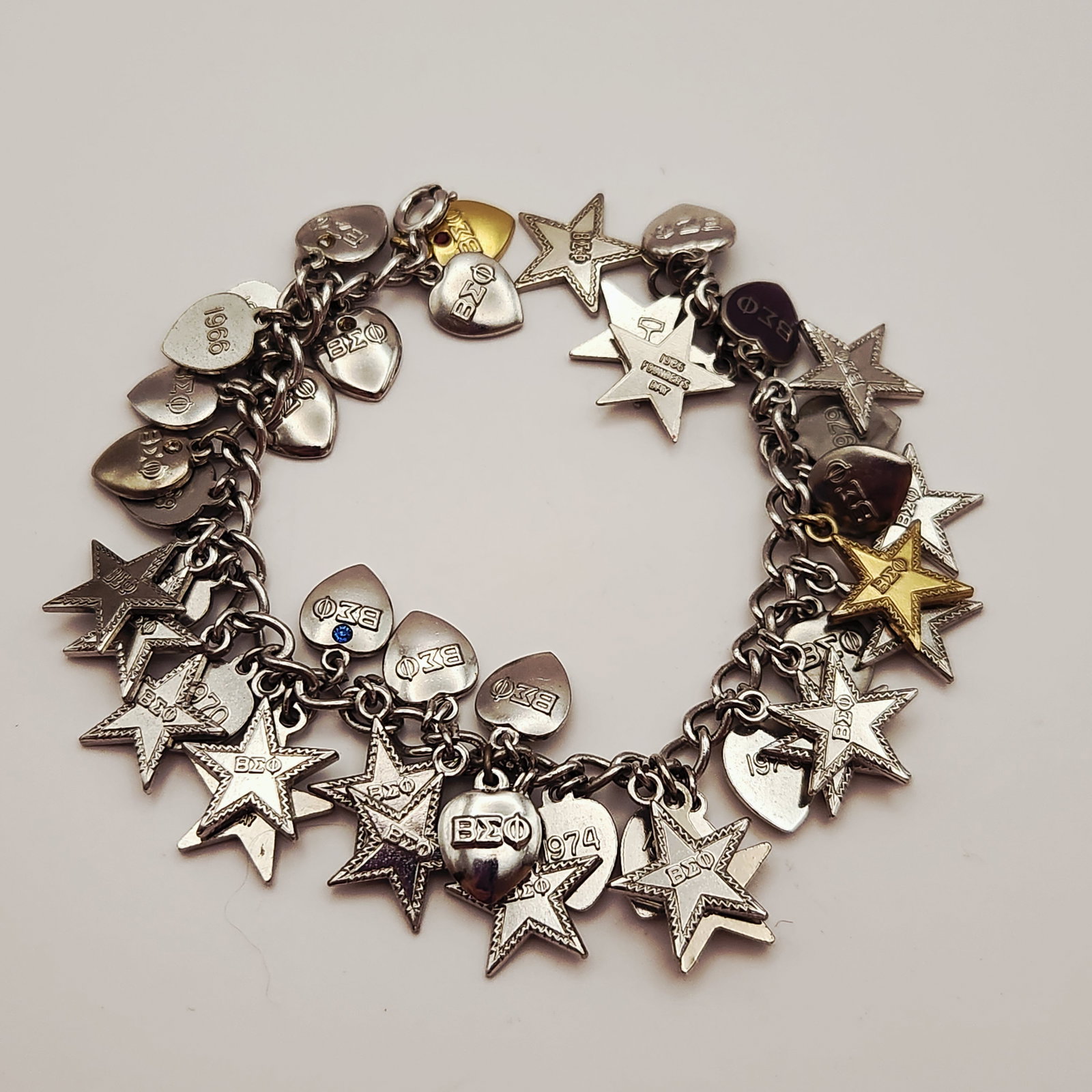 Beta Sigma Phi Charm Bracelet: This sterling silver curb link charm bracelet features an assortment of charms associated with the Beta Sigma Phi sorority. The collection includes textured five-pointed stars and heart-shaped charms