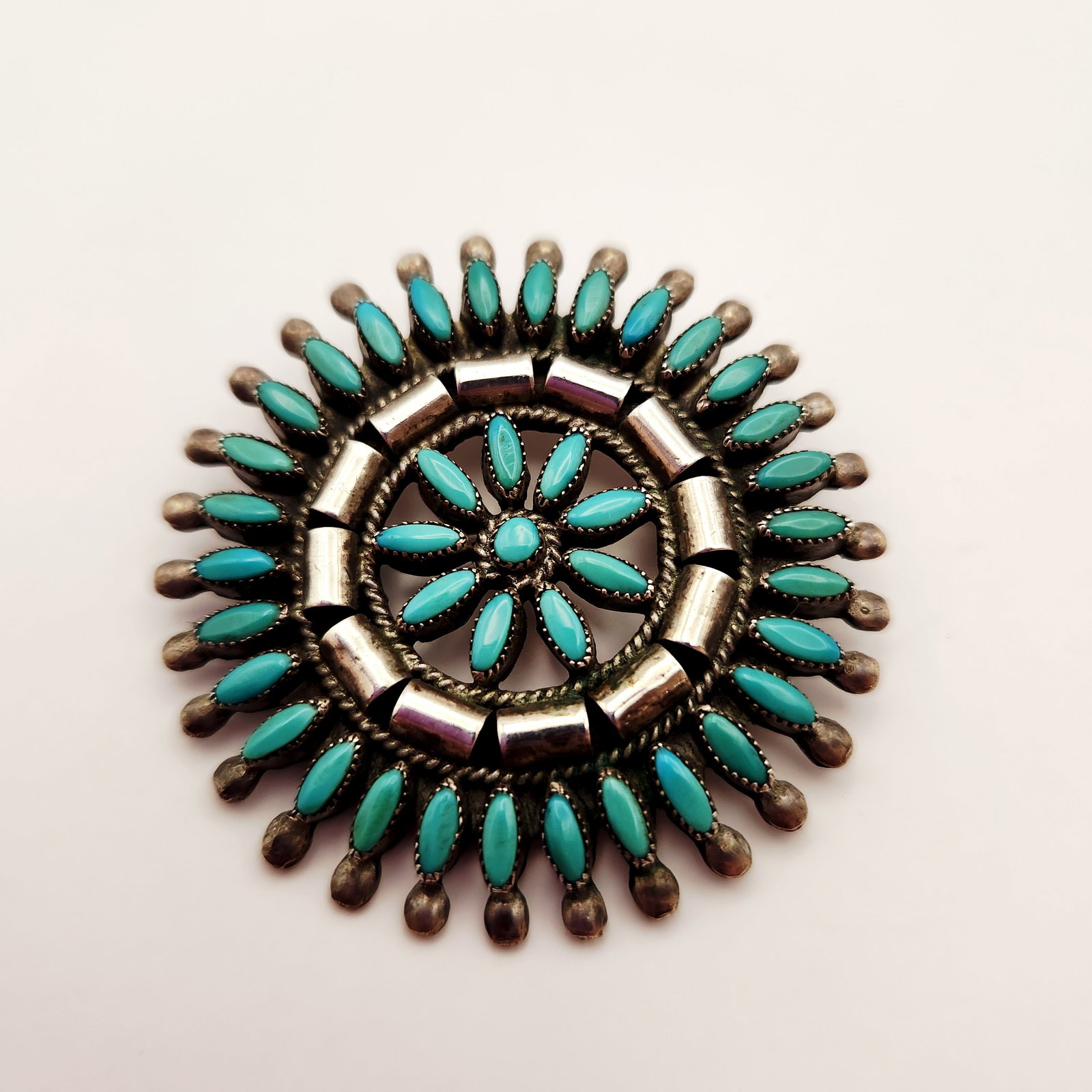 Andrew Dewa Zuni Turquoise Brooch 13.9 Grams: This handcrafted sterling silver sunburst brooch features thirty-four needlepoint turquoise stones set in delicate serrated bezels by Zuni artist Andrew Dewa. Measuring 2 inches in diameter &