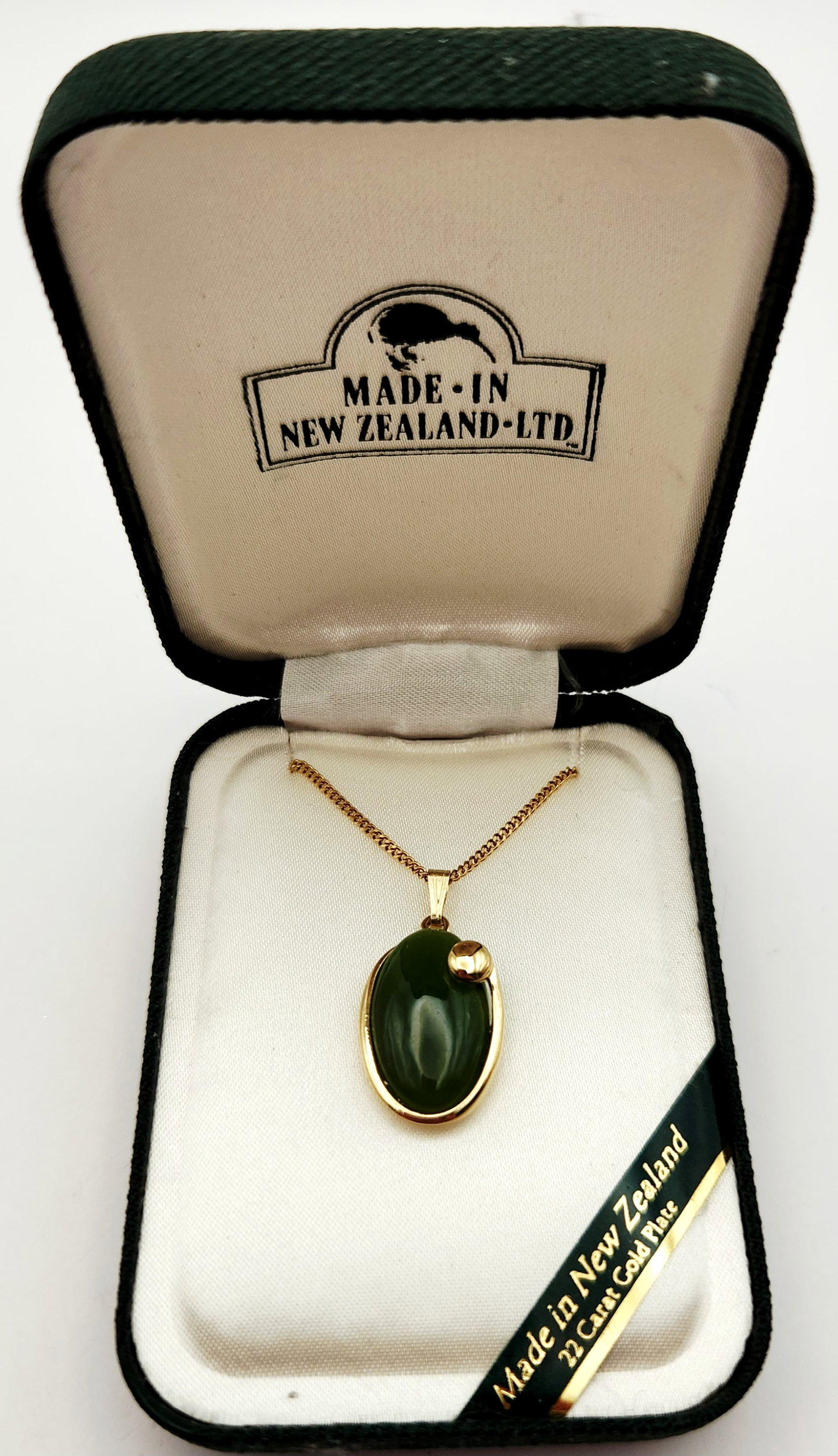 Ariki New Zealand Greenstone Pendant Necklace: This Ariki pendant necklace features an oval cabochon greenstone set in a 22-karat gold-plated mount. Pendant length: 1 inch Chain length: 18 inches. The necklace is in excellent condition with no