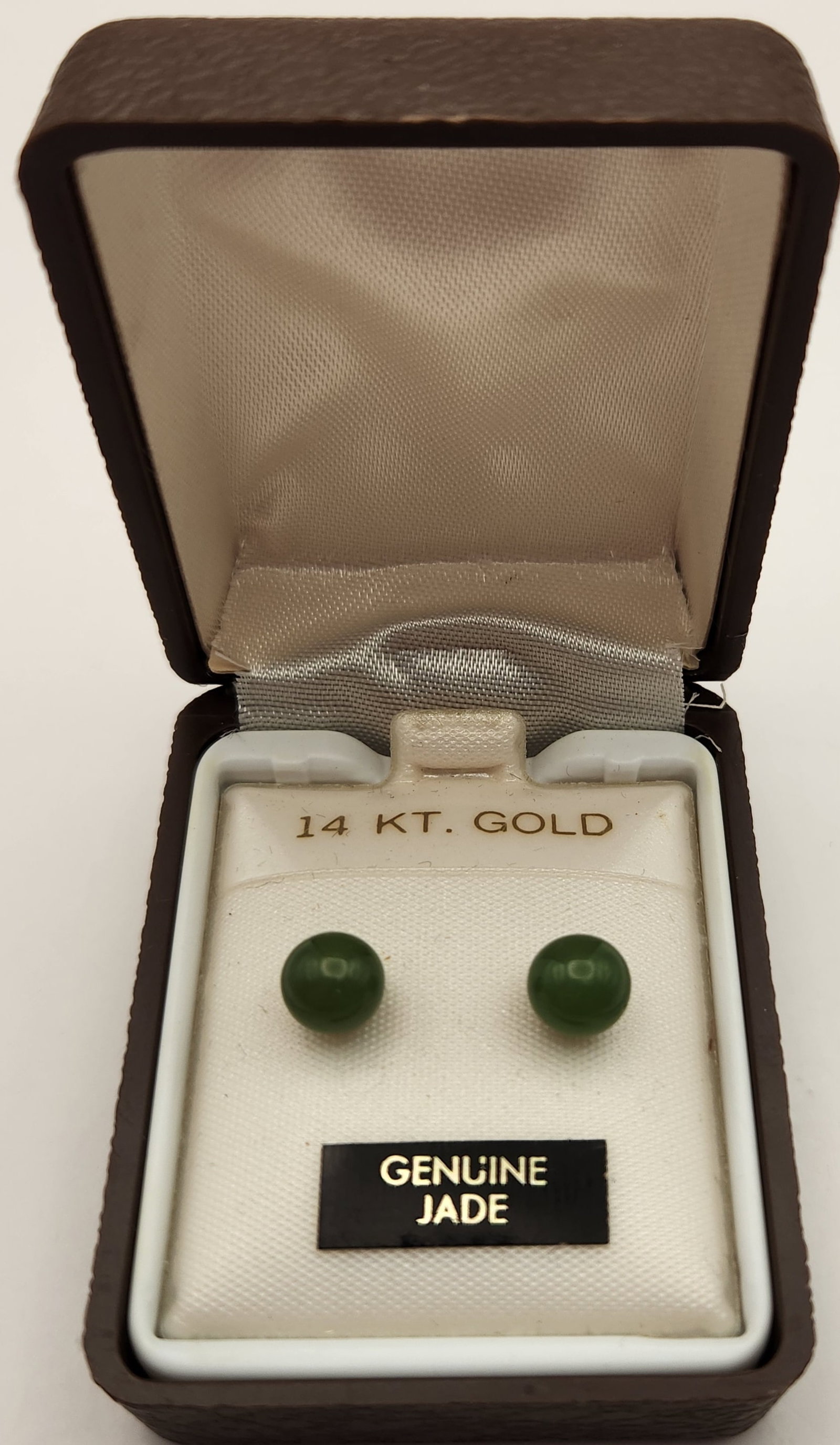 14K Gold Jade Studs Earrings: A matched pair of stud earrings featuring spherical dark green jade beads set in 14kt yellow gold. Each earring post is stamped 14K and the accompanying butterfly backings are likewise marked 14K. The