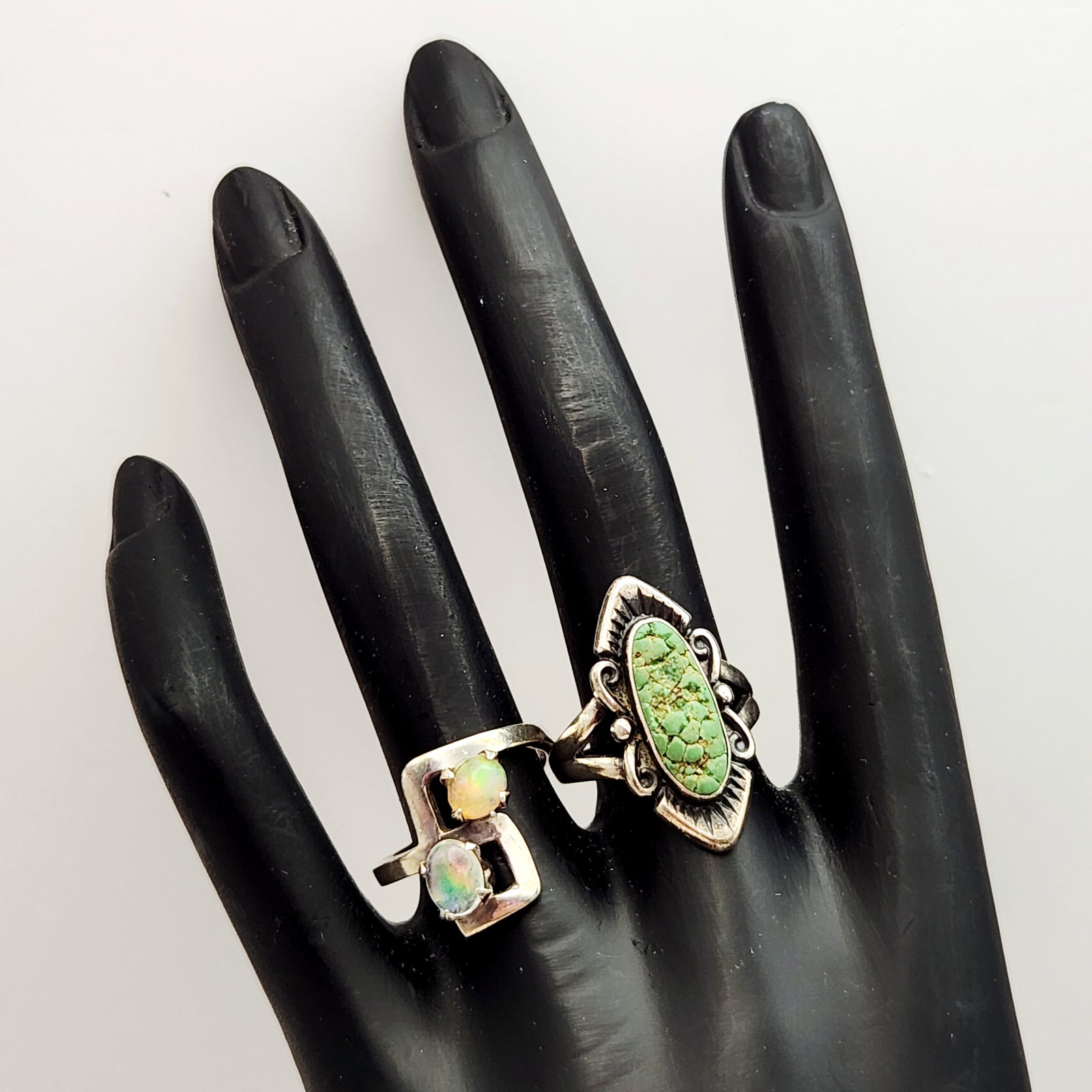 Vintage Sterling Gemset Rings 8.6 Grams: An assortment of two rings including a Southwestern-style statement ring and a modernist geometric bypass ring. The statement ring features an elongated marquise-shaped green turquoise mosaic