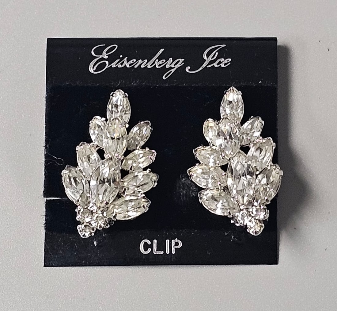 Eisenberg Ice Rhinestone Leaf Clip-On Earrings: A pair of silver-toned costume jewelry earrings by Eisenberg Ice featuring a tiered cluster of clear marquise and round rhinestones in a stylized leaf motif. The earrings measure approximately 1.5