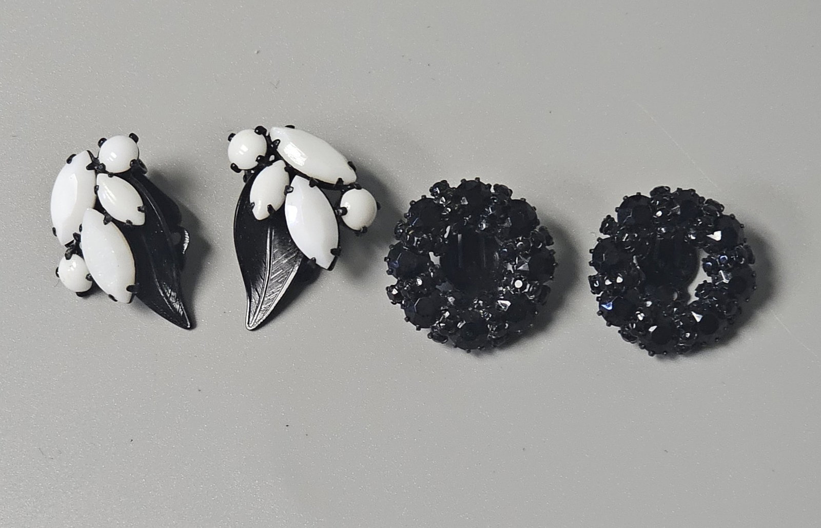 Two Pairs of Weiss Earrings: This lot features a pair of leaf-form clip-on earrings and a pair of circular wreath cluster clip-on earrings, both crafted from japanned black-finished metal. The leaf earrings measure 1 1/4 inches i