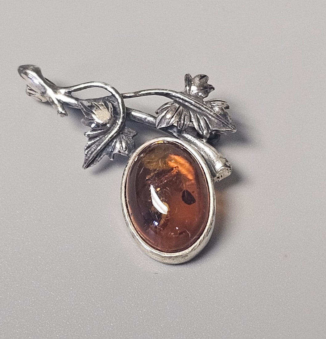 Polish Sterling Silver Amber Brooch: This vintage Polish sterling silver brooch features a textured foliate branch design accented with a Baltic amber cabochon. The pin stem is stamped with the Polish post-1986 hallmark for .925 silver a
