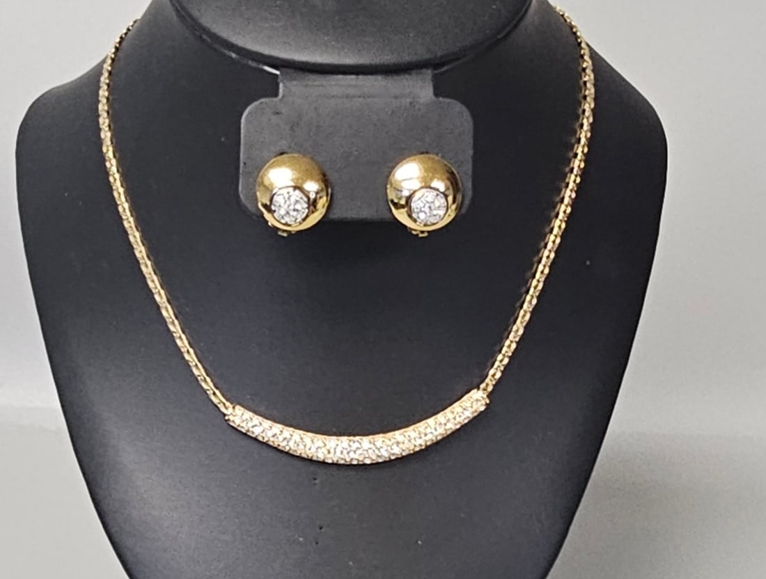 Swarovski Gold-Plated Pave Crystal Necklace & Earrings: A Swarovski jewelry set featuring a gold-plated necklace with a crystal-embellished bar pendant and matching domed clip-on earrings. The necklace consists of a snake-style chain supporting a central c