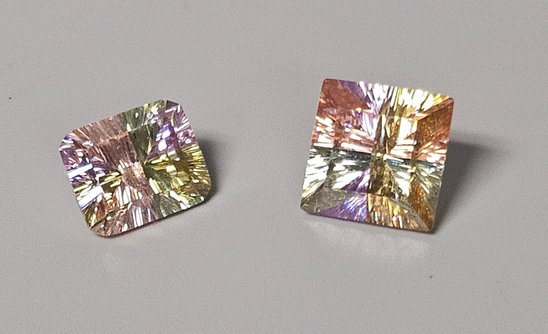 Multi-Color Cubic Zirconia Gemstones: An assortment of two loose synthetic cubic zirconia gemstones, each displaying a distinctive tri-color zoning pattern in vibrant shades of pink, yellow, and light green. The gemstones feature complex
