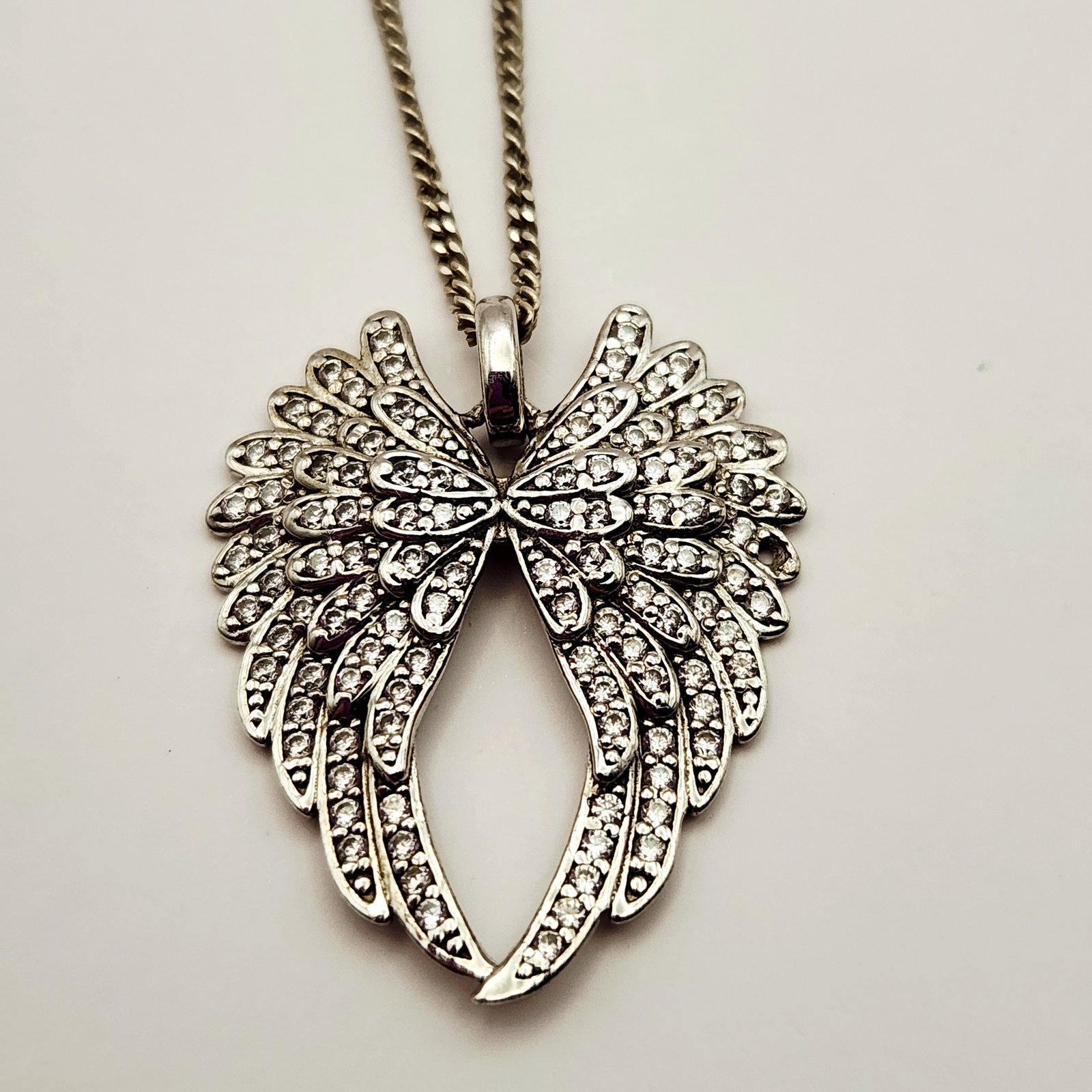 Sterling Angel Wing Necklace 6.8 Grams: A Chinese sterling silver pendant necklace featuring a pair of openwork angel wings. The reverse of the pendant is impressed with a stylized E monogram followed by CZ 925 and CHINA, with an
