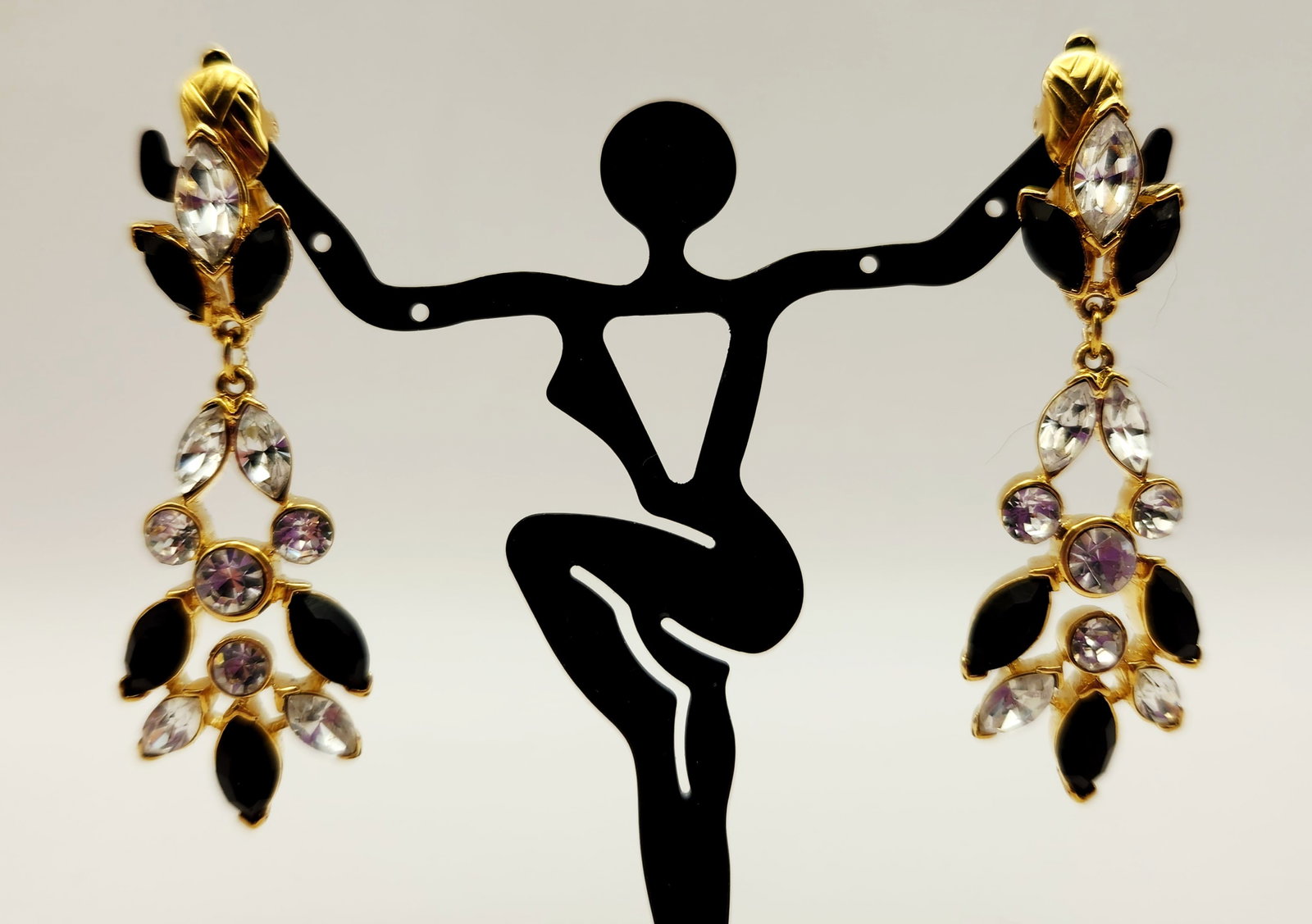 Crown Trifari Chandelier Clip Earrings: This matched pair of articulating chandelier-style drop earrings is crafted in gold-tone metal with a three-tiered design. Length: 2.5 inches (6.4 cm). These earrings are in excellent vintage