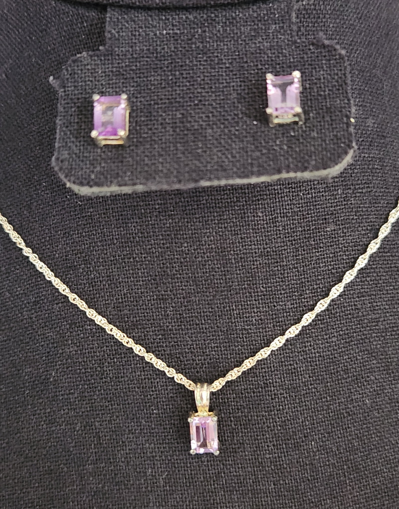 Sterling Amethyst Jewelry Set 3.5 Grams: This jewelry set comprises a pendant necklace and matching stud earrings featuring emerald-cut purple gemstones appearing to be amethyst in four-prong basket settings. Weight: 3.5 grams Necklace