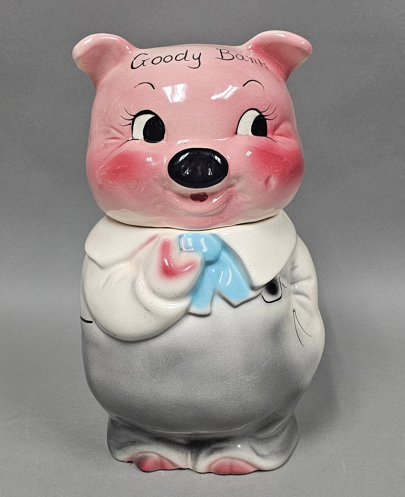 Shawnee Pottery Goody Bank Pig Jar: A vintage ceramic lidded jar produced by Shawnee Pottery, designed in the form of an anthropomorphic pig. The piece is constructed in two sections with a head that serves as a lid and a bulbous body