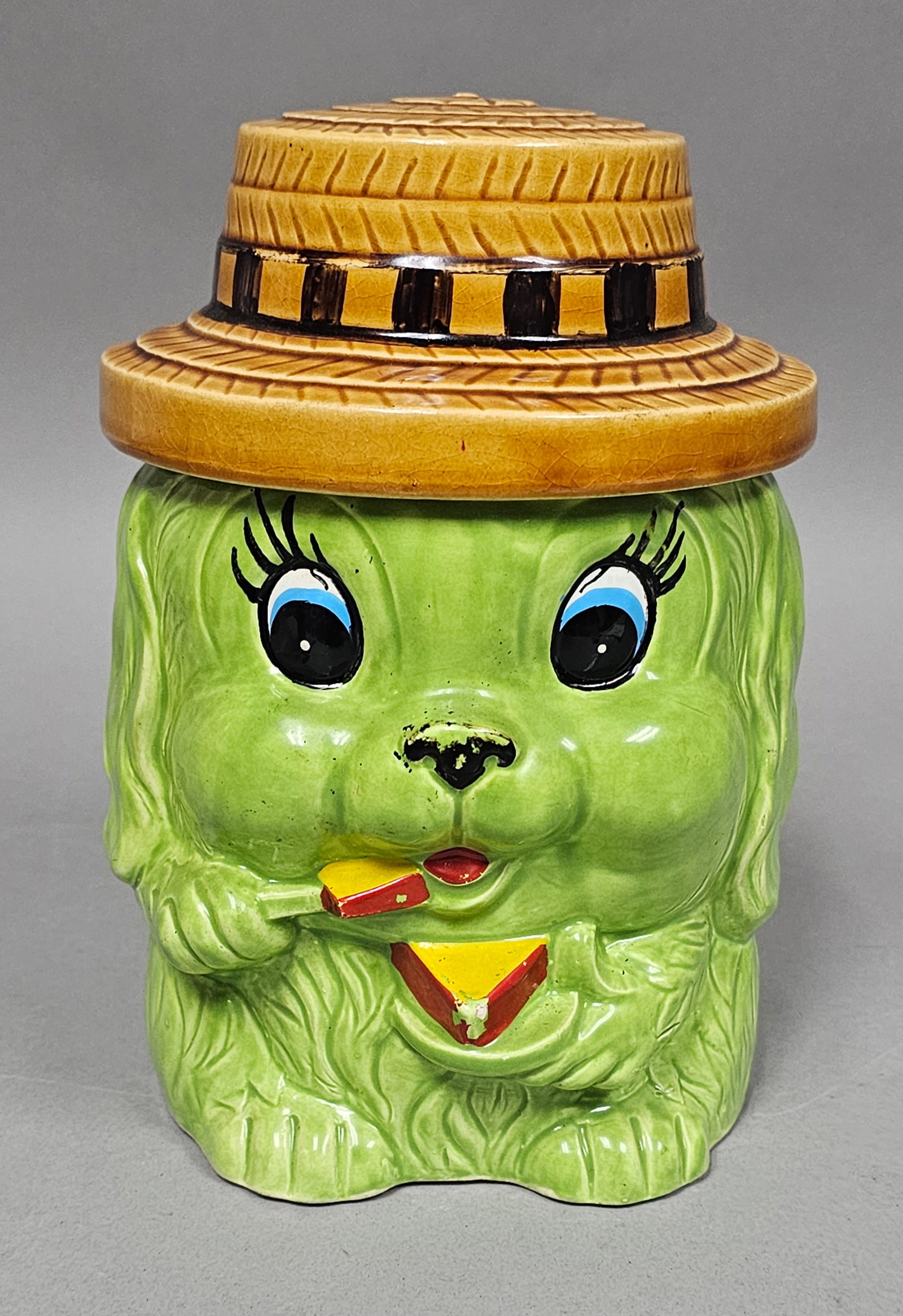 Japan Ceramic Green Dog Cookie Jar: A vintage Japanese glazed earthenware cookie jar featuring an anthropomorphic green dog wearing a molded straw boater-style hat. The base is impressed with the mark JAPAN in block capitals.