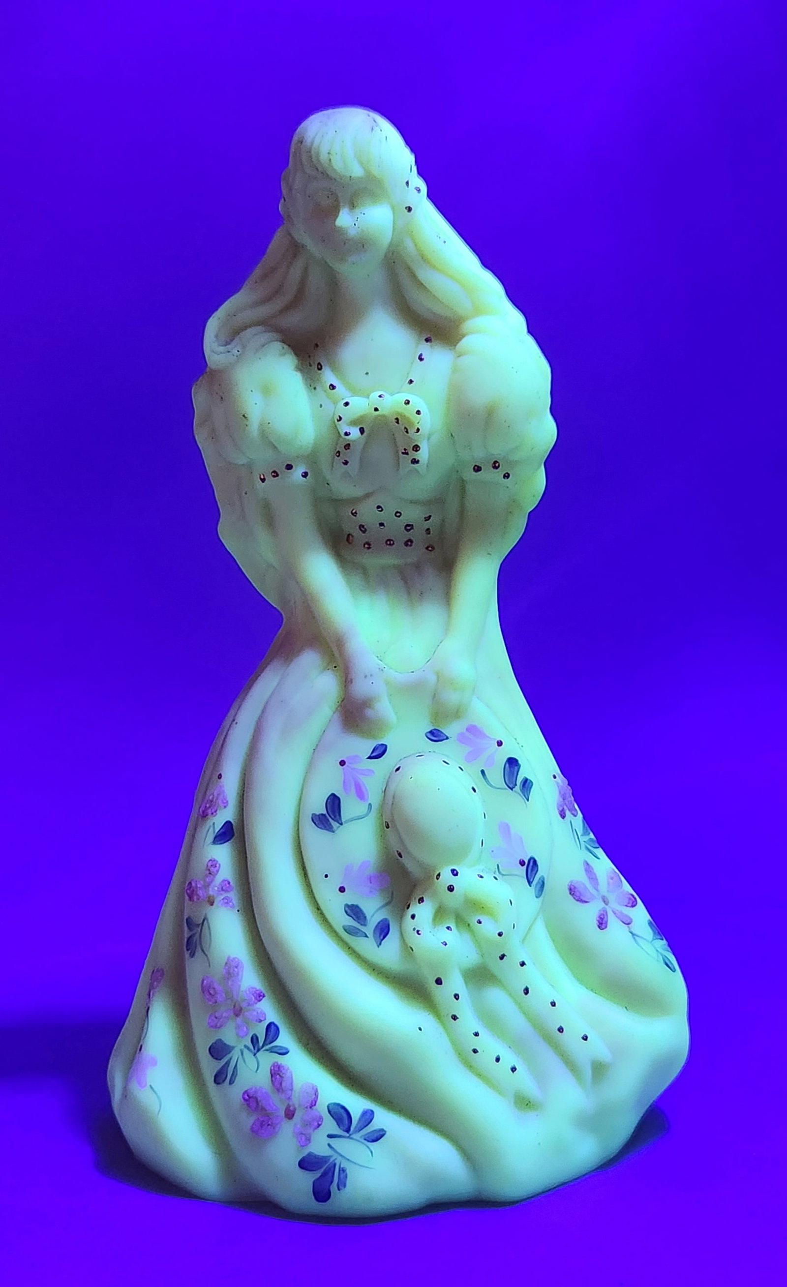 Fenton Awaiting the Groom Figurine: A Fenton Art Glass figurine titled Awaiting the Groom, fashioned from hand-painted custard glass with a satin finish and pink blush accents. The uranium-bearing glass exhibits a bright green