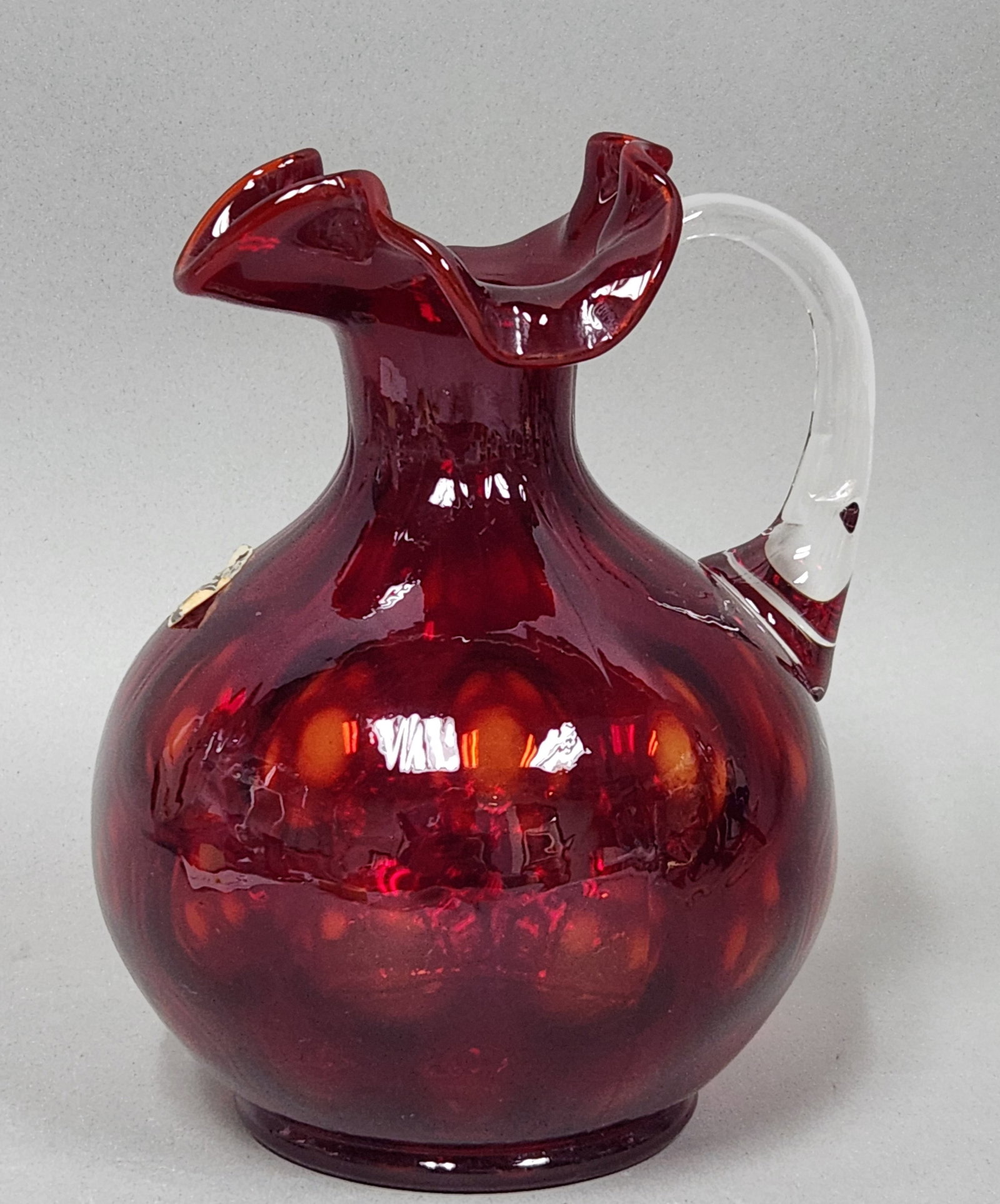 Fenton Ruby Coin Dot Pitcher: This Fenton Art Glass pitcher features a deep ruby red body with a mold-blown coin dot optic pattern. The piece retains an original silver and black foil label indicating it is authentic Fenton