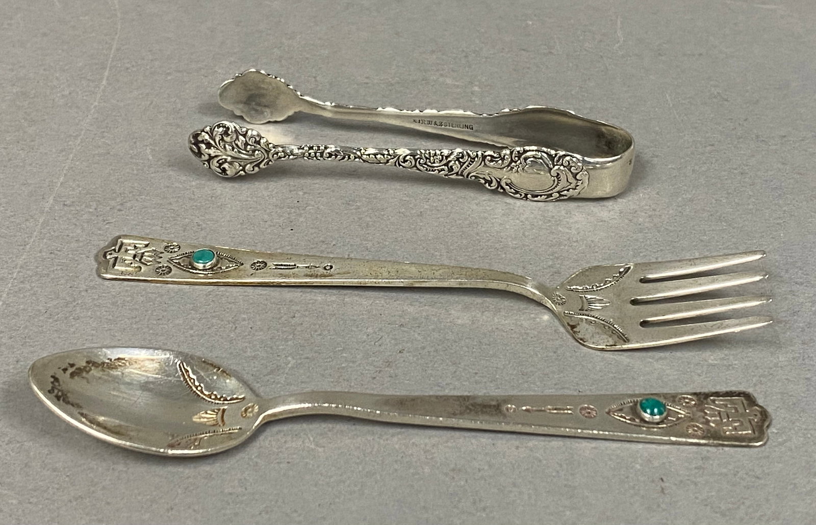 Wallace Sterling Grande Baroque Tongs & Southwestern Flatware: A three-piece assortment of sterling flatware. The group includes a pair of sugar tongs in the Grande Baroque pattern by R. Wallace & Sons. The interior handle is impressed with a mark featuring a