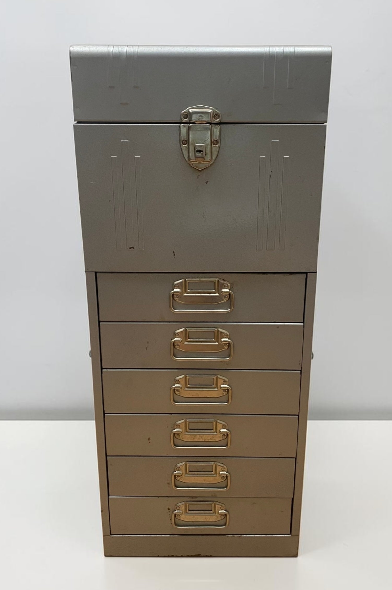 Hammered Steel Multi-Drawer Storage Cabinet: This mid-century industrial storage cabinet is constructed from steel with a textured silver-grey hammertone painted finish. The unit features a slanted top-access compartment secured by a hinged lid