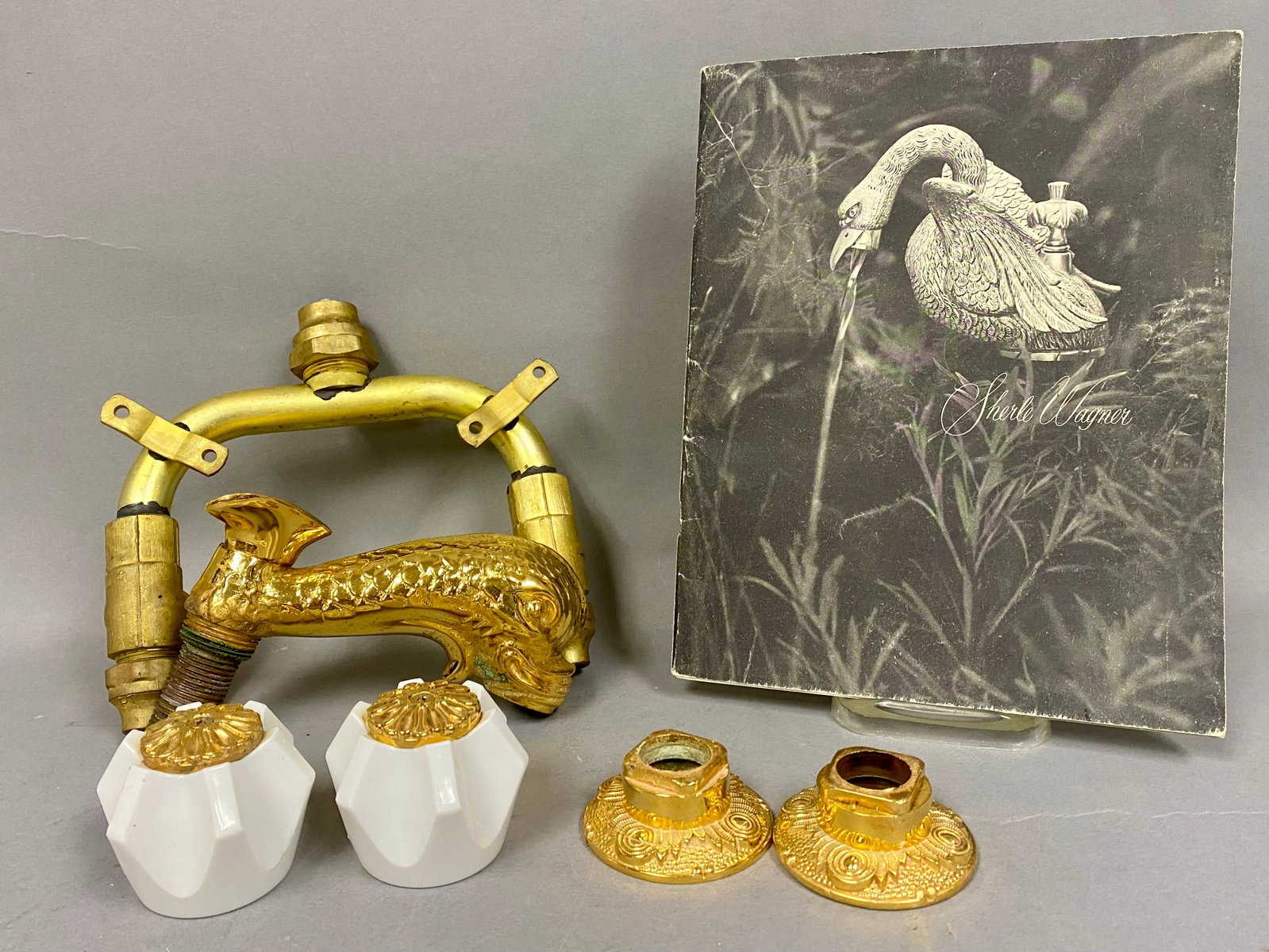 Sherle Wagner 24K Gold-Plated Dolphin Faucet Set: This vintage Sherle Wagner bathroom faucet set features a central spout cast in the form of a stylized dolphin with detailed scales and a bifurcated tail fin crest. The set is composed of two