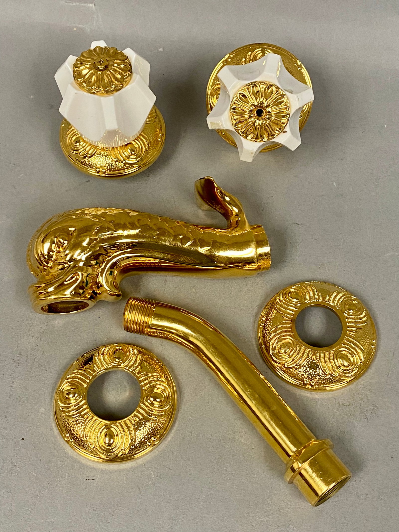 Sherle Wagner 24K Gold-Plated Dolphin Faucet: The collection centers on a cast brass figural spout modeled as a dolphin with textured scales and a flared water outlet. Two matching handles are constructed with six-pointed star-shaped white