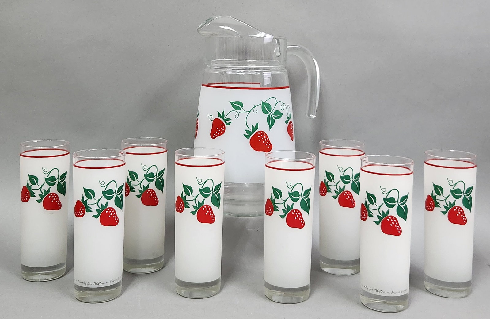 Teleflora France Strawberry Pitcher & Tumblers: A vintage nine-piece glass beverage set manufactured for Teleflora, consisting of one pitcher and eight highball tumblers. A script mark along the base of the frosted band on all pieces reads Made