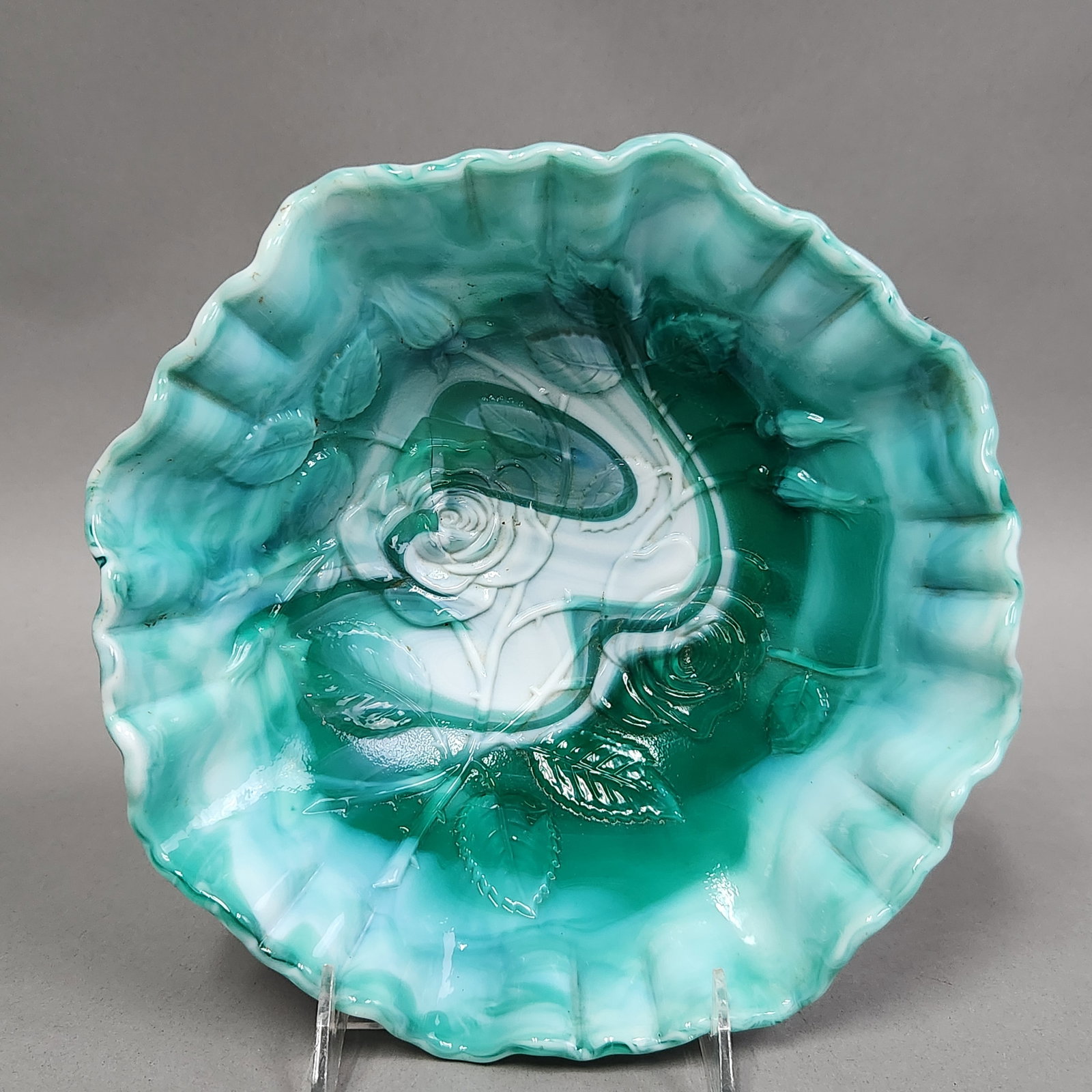 American Green Slag Glass Rose Ruffled Bowl: An American pressed slag glass bowl featuring a swirled emerald green and opaque white color palette. The vessel is decorated with high-relief floral motifs including roses, buds, and leaves across bo